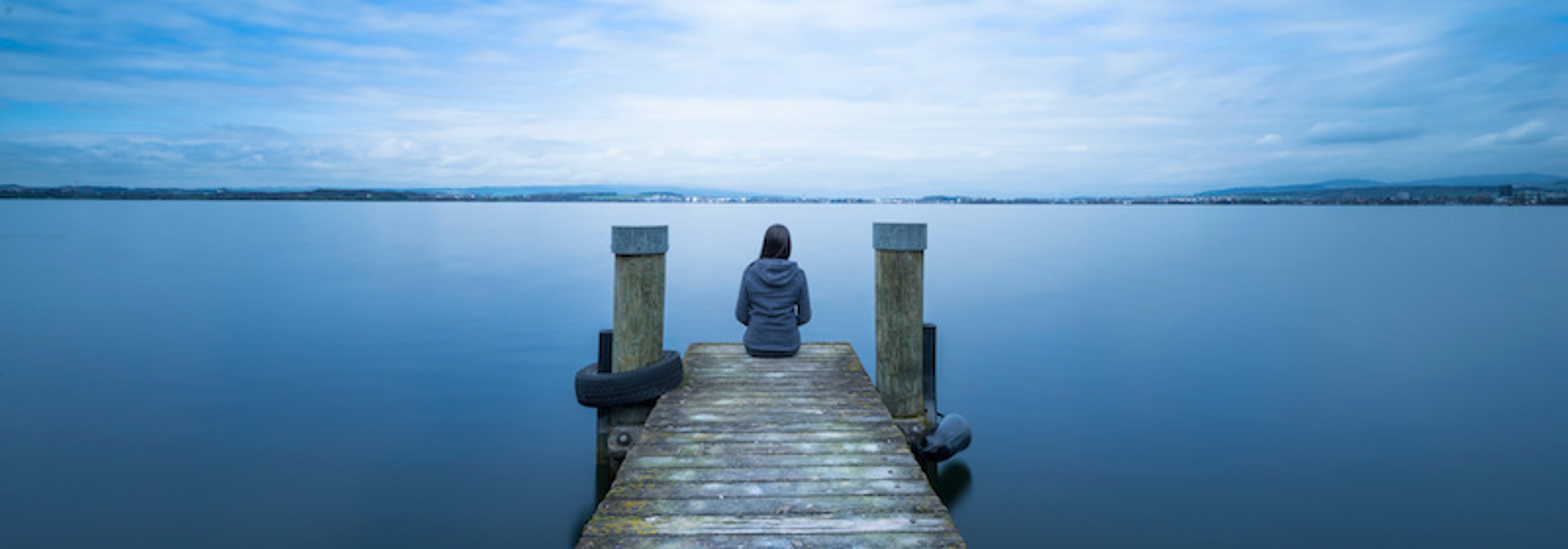 Women sitting on the end of a dock expressing loneliness