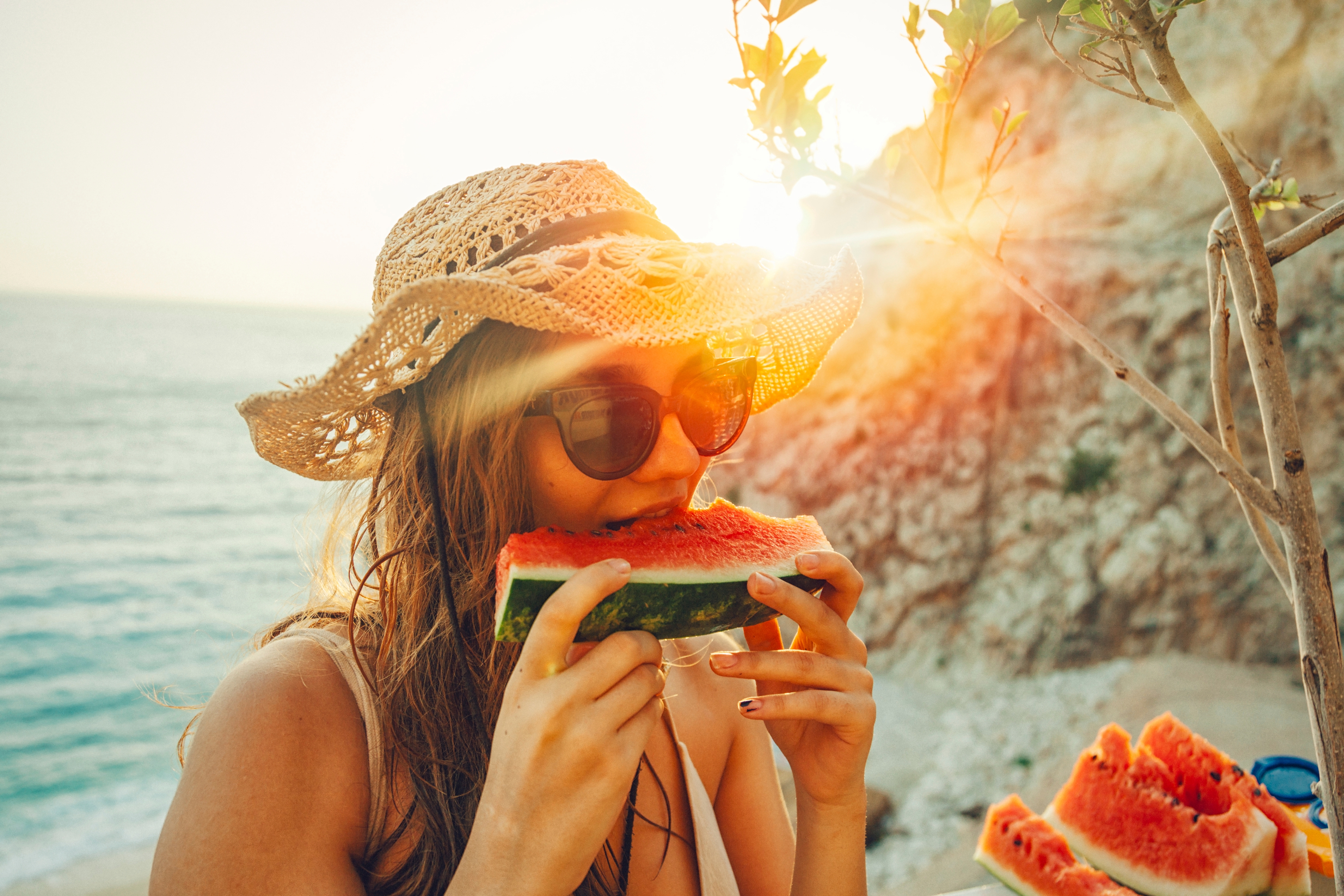 Article Cards Featured Image young woman having fun and eating juicy fresh watermelon outdoor at sunset time with snuffler in summer time