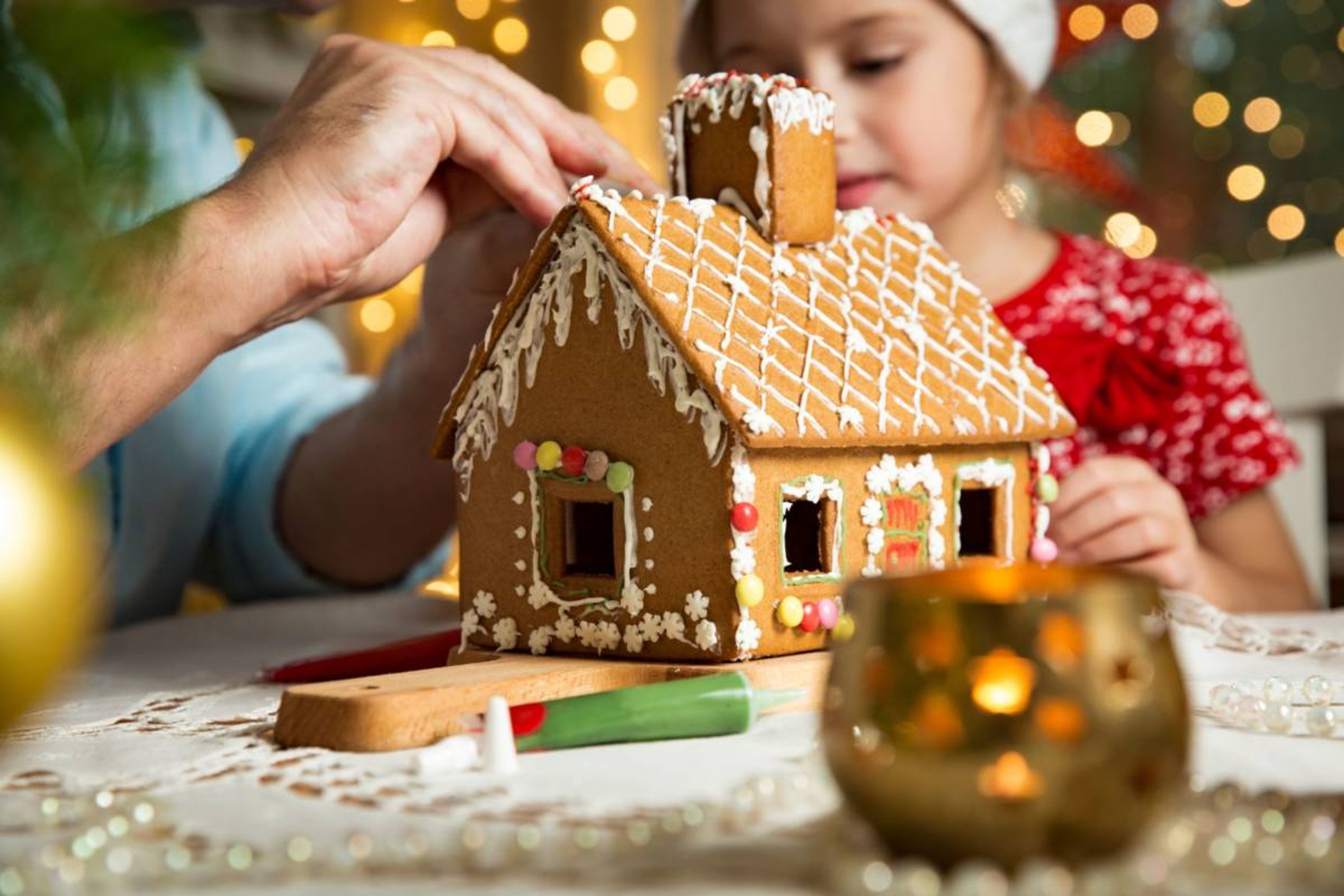 Adult and child making a Christmas themed gingerbread house