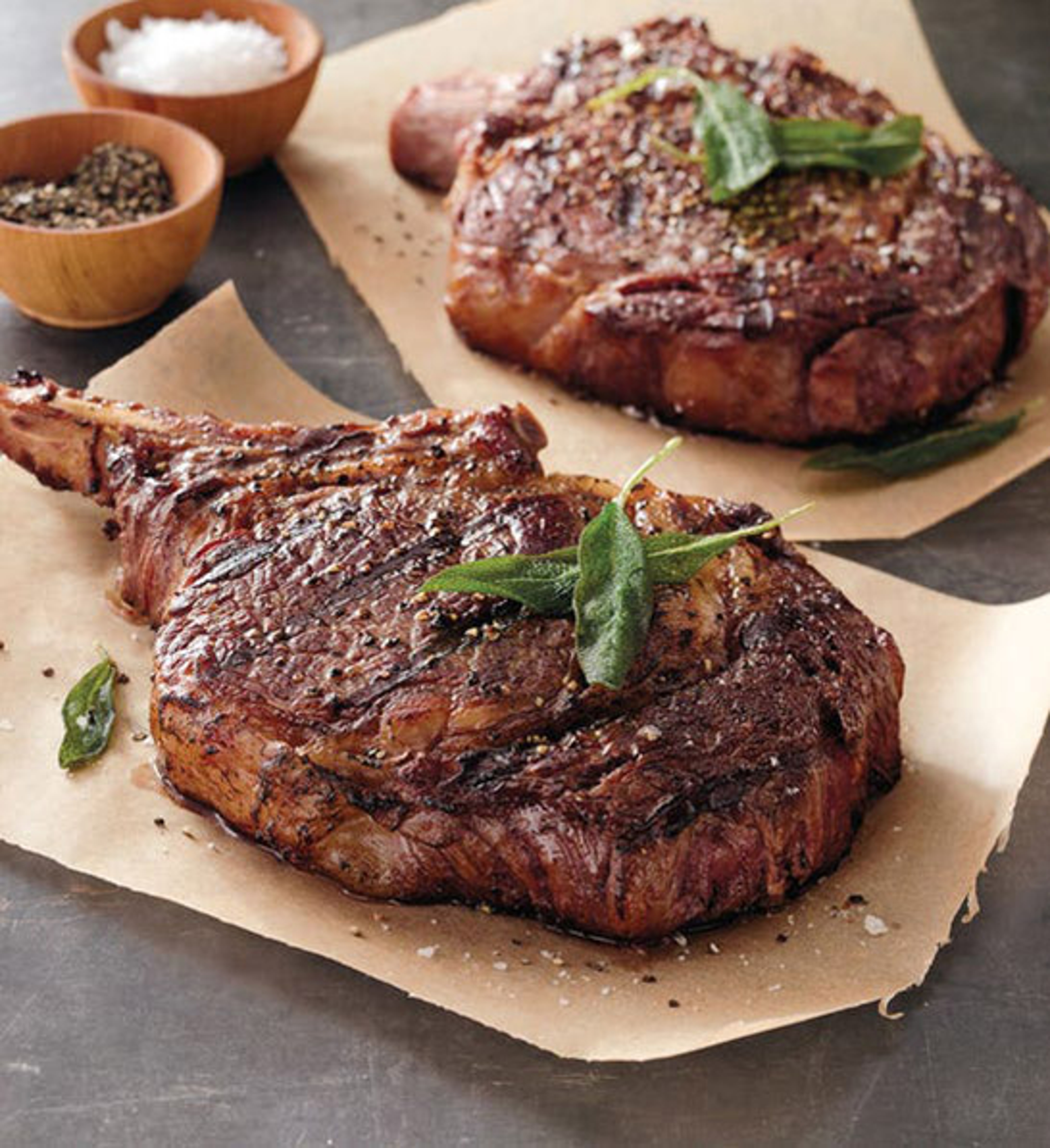 anniversary gift guide image grilled bone in ribeye steak on wax paper with spices in the background.