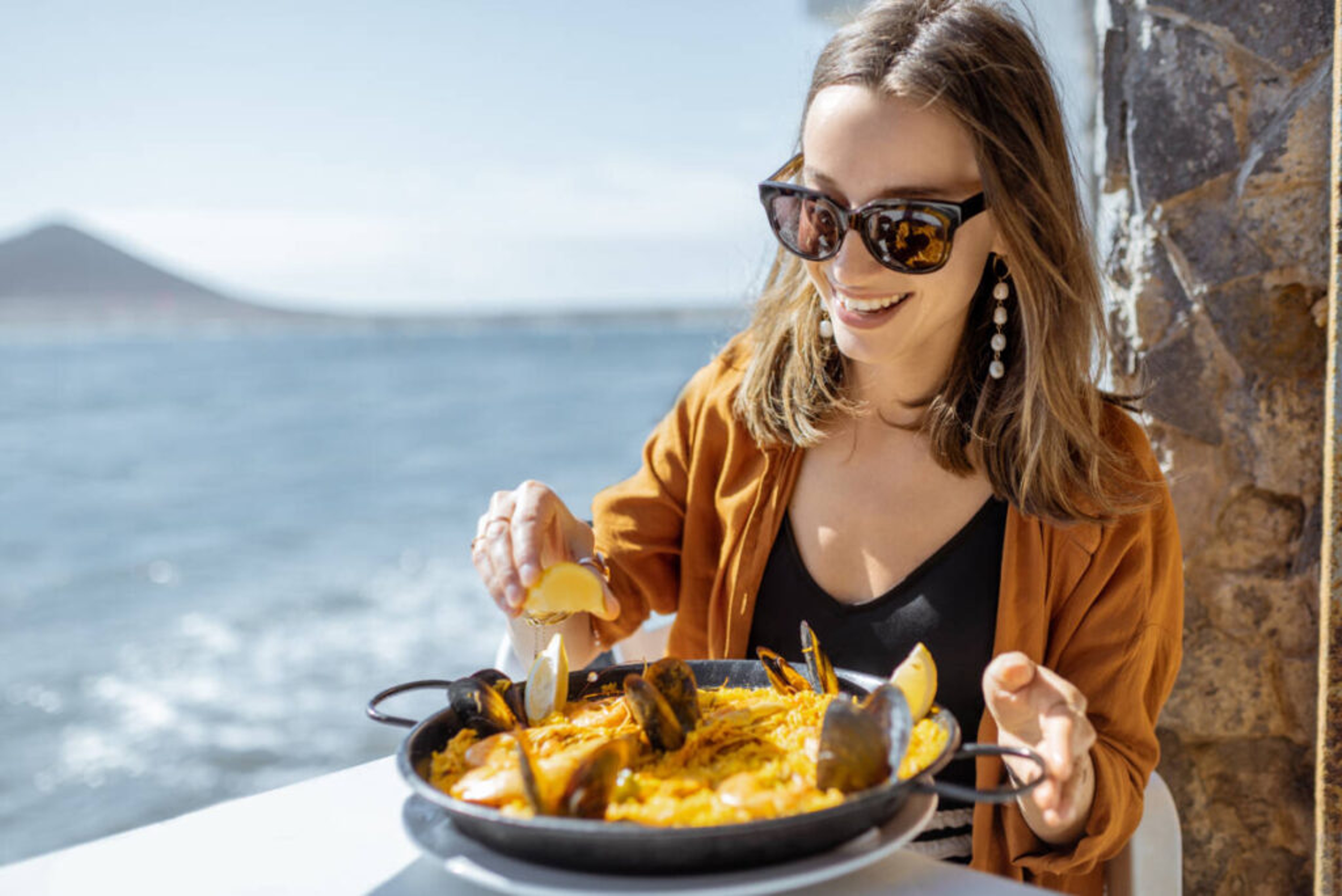 Woman eating a Mediterranean diet by the sea.