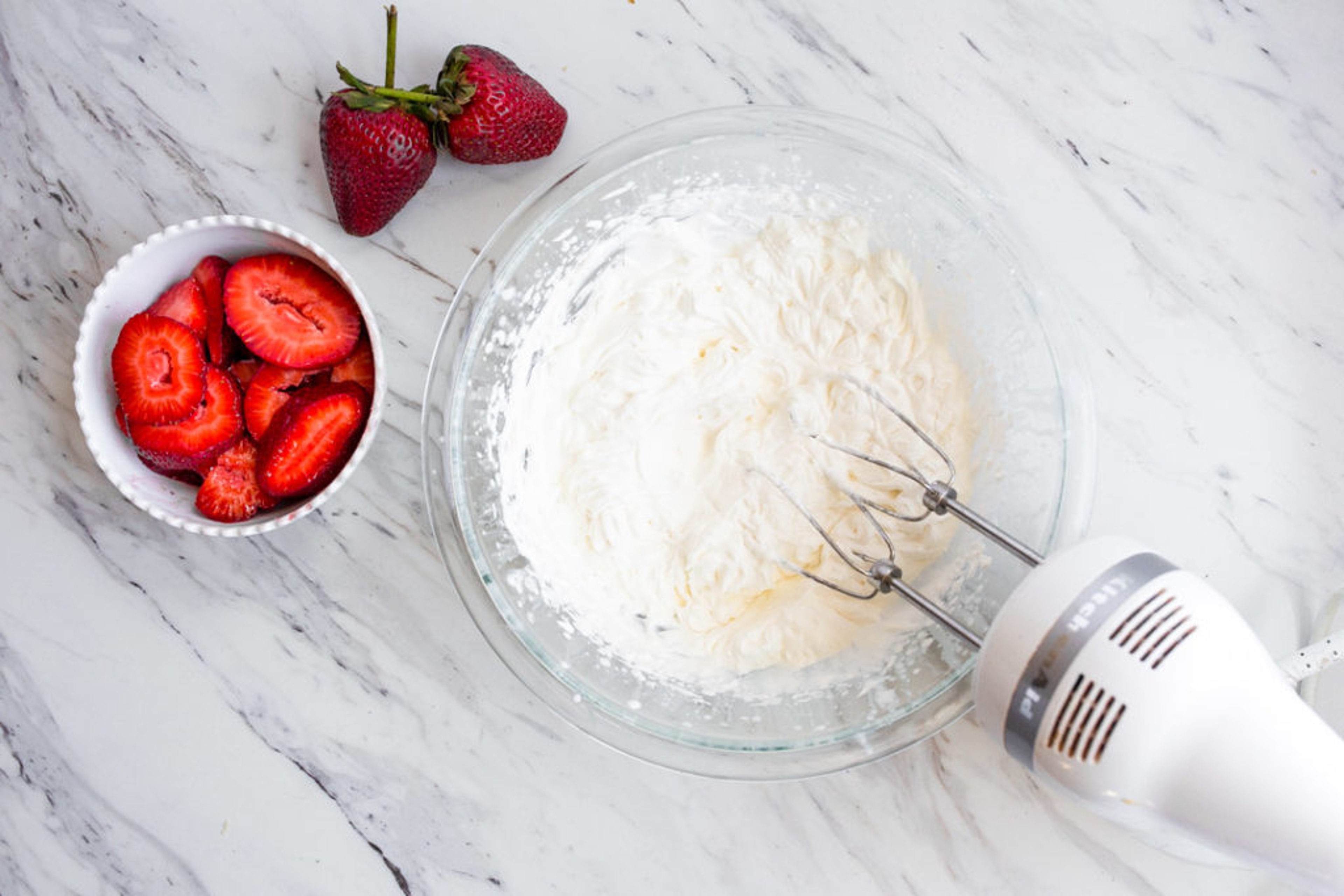 Sliced strawberries and whipped cream for strawberry crepes.