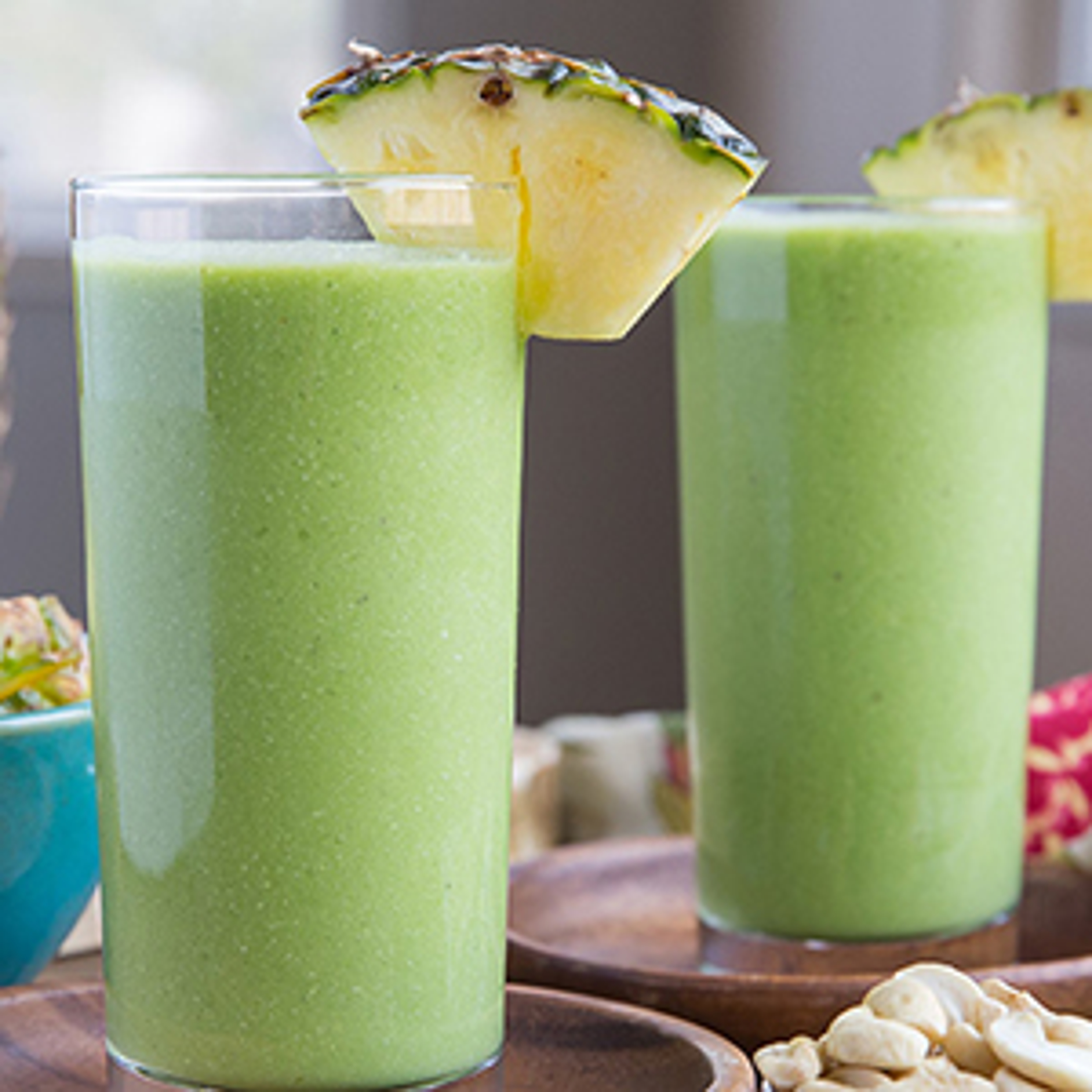 Two glasses of green pineapple smoothie with a pineapple garnish
