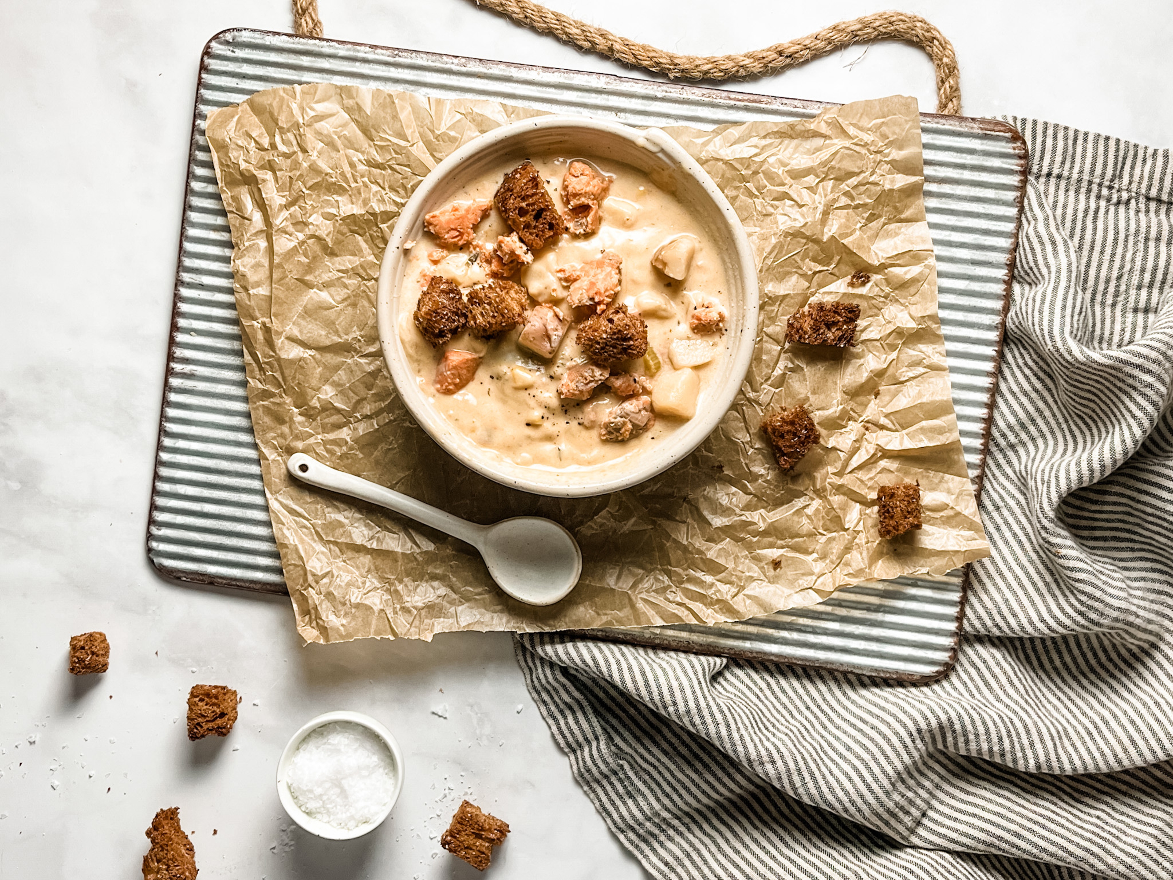 Article Cards Featured Image fish soup recipes bowl of salmon chowder on a table with utensils and accompaniments