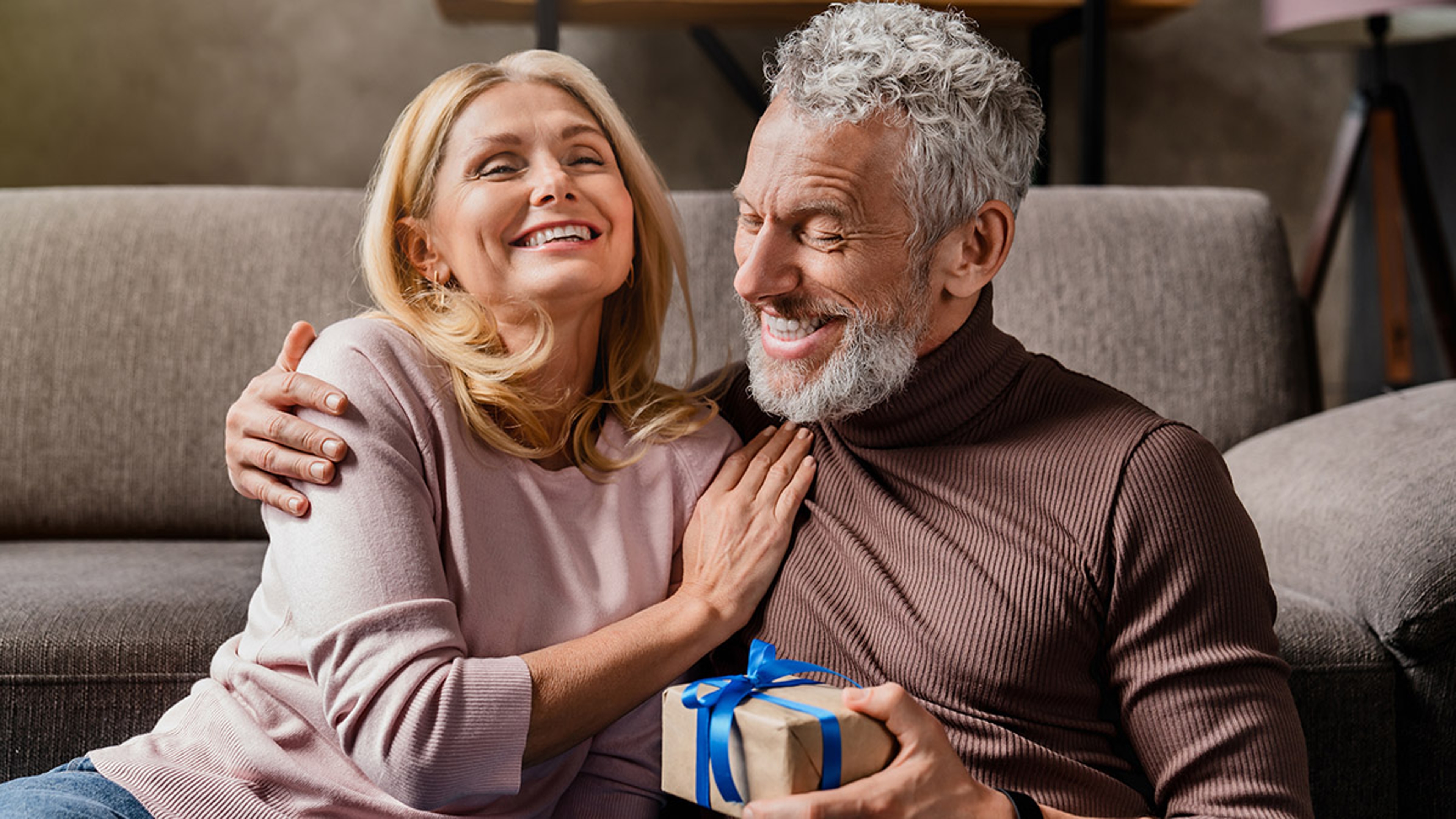 Article Cards Featured Image Loving middle aged man making surprise by giving gift in box to his wife celebrating anniversary or birthday at home