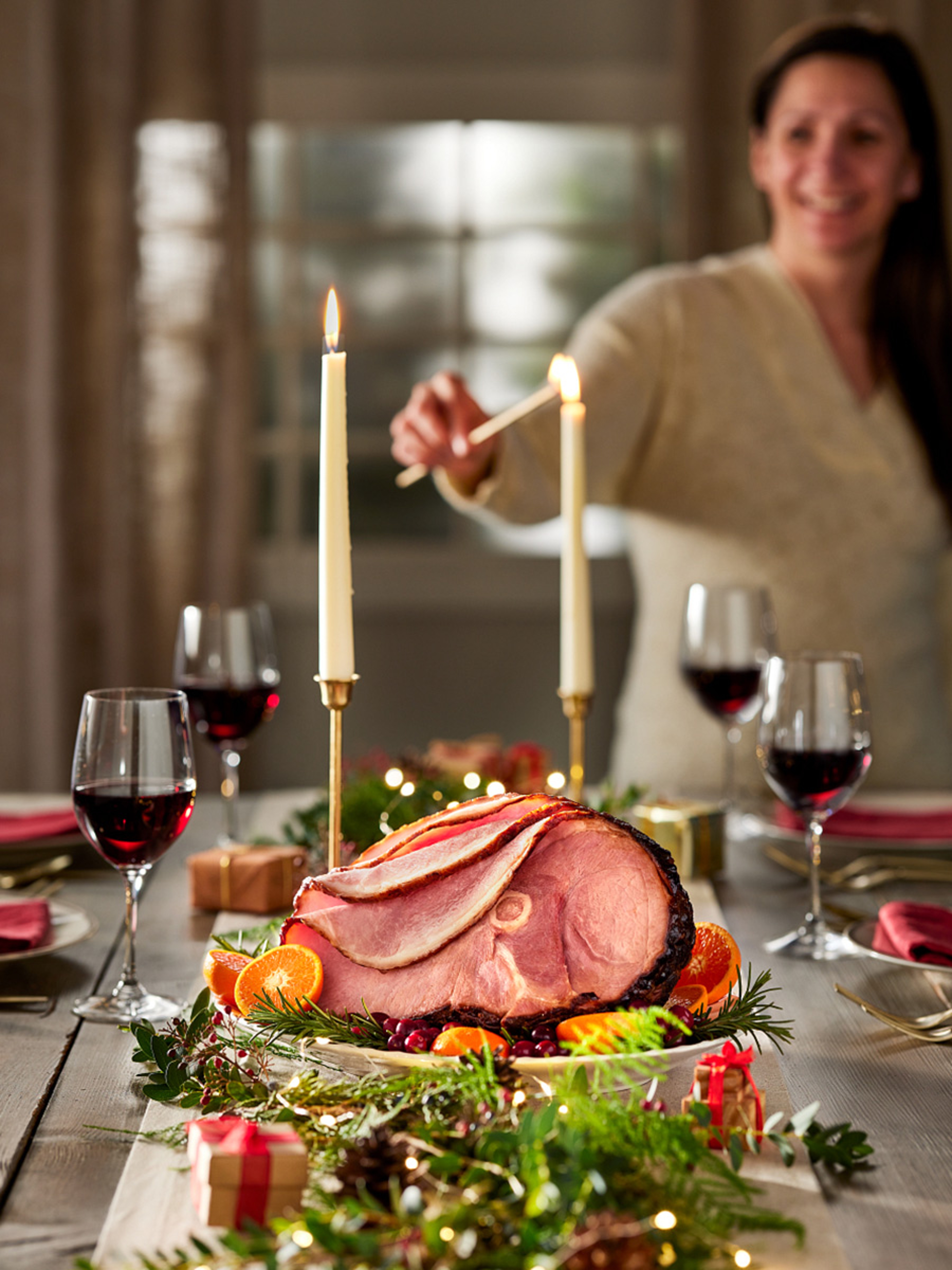 Woman lighting candles at a holiday dinner party.