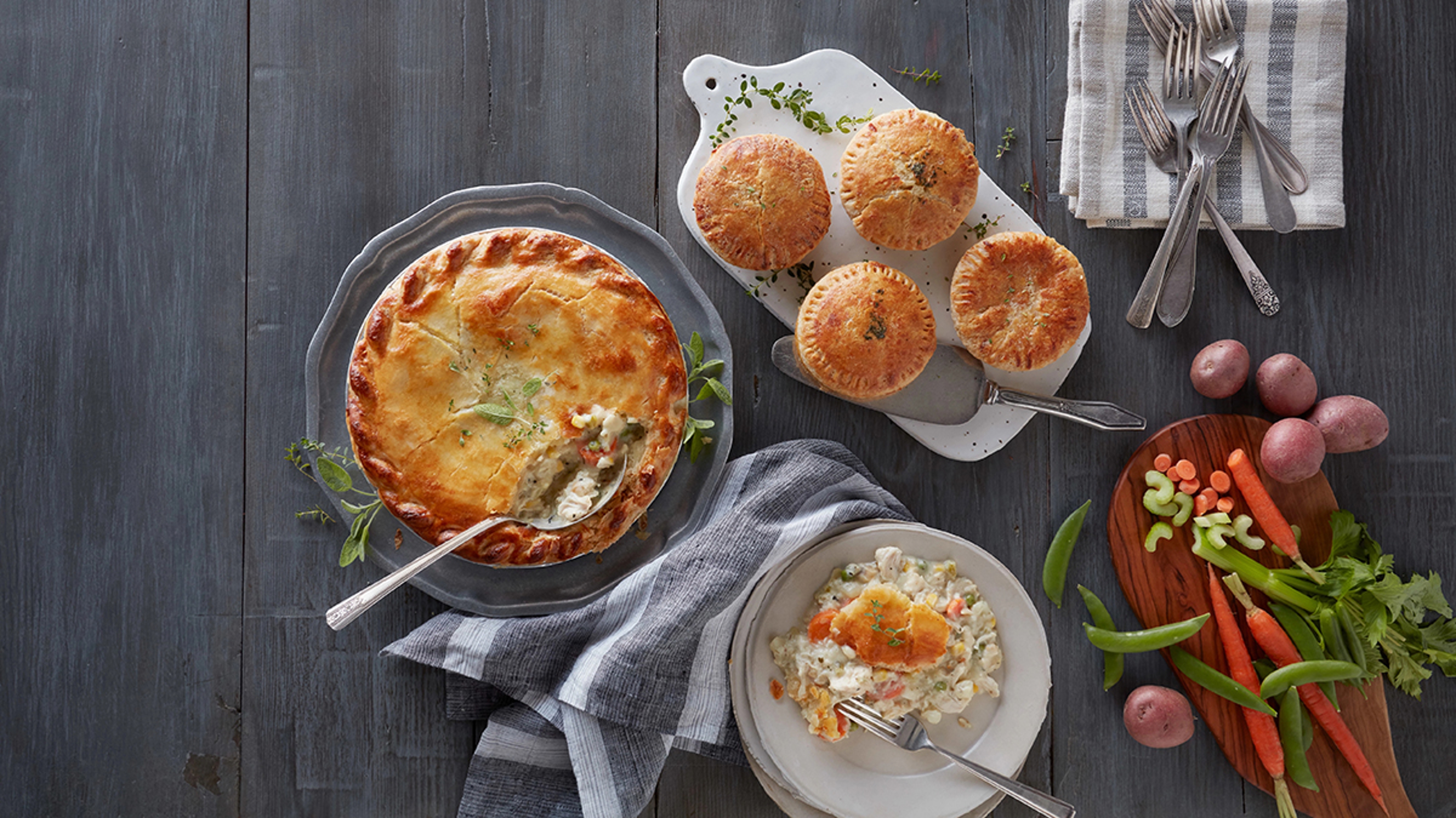 Several pot pies on platters next to ingredients.