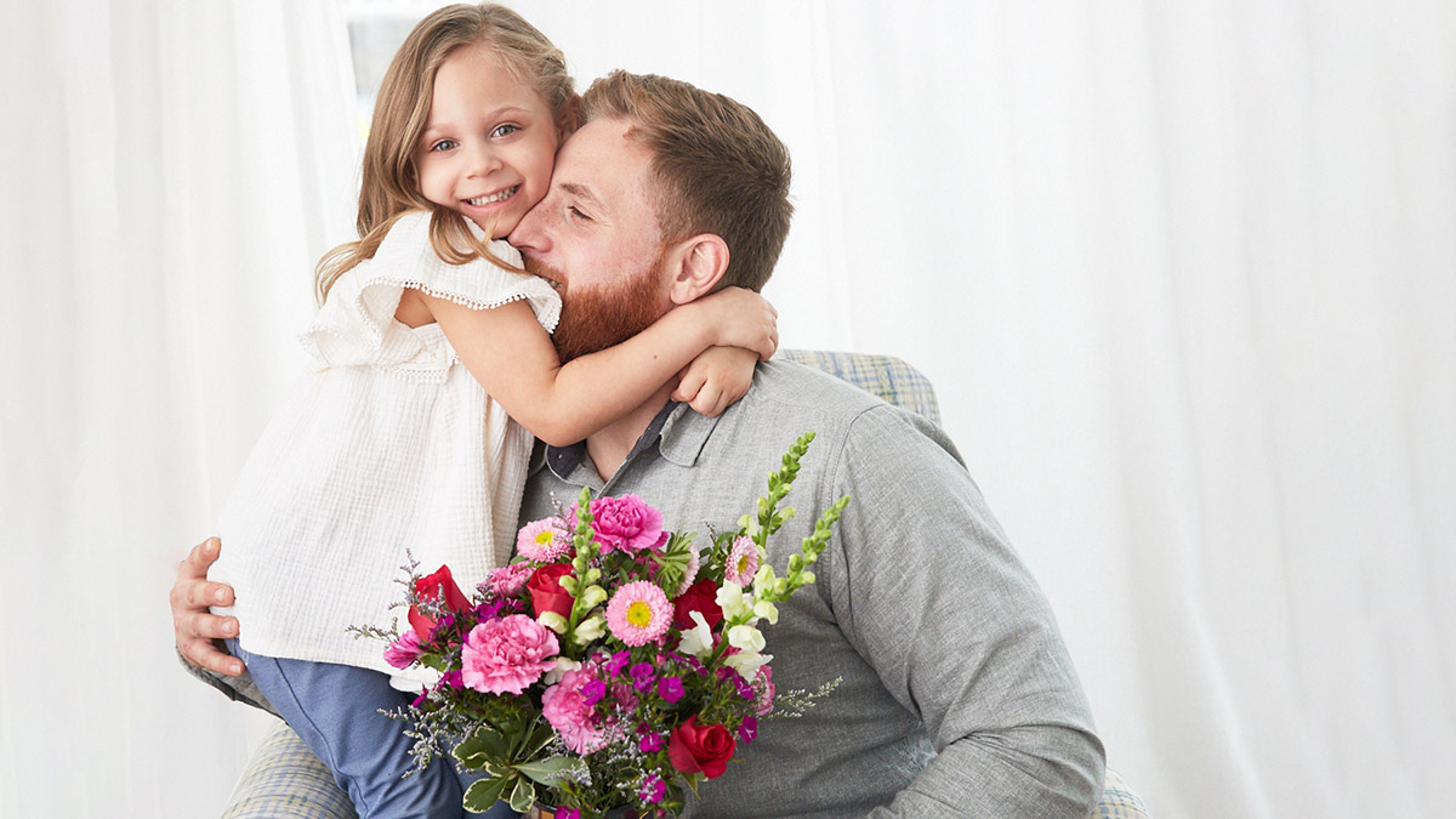 history of mothers day with father and daughter embracing with flowers