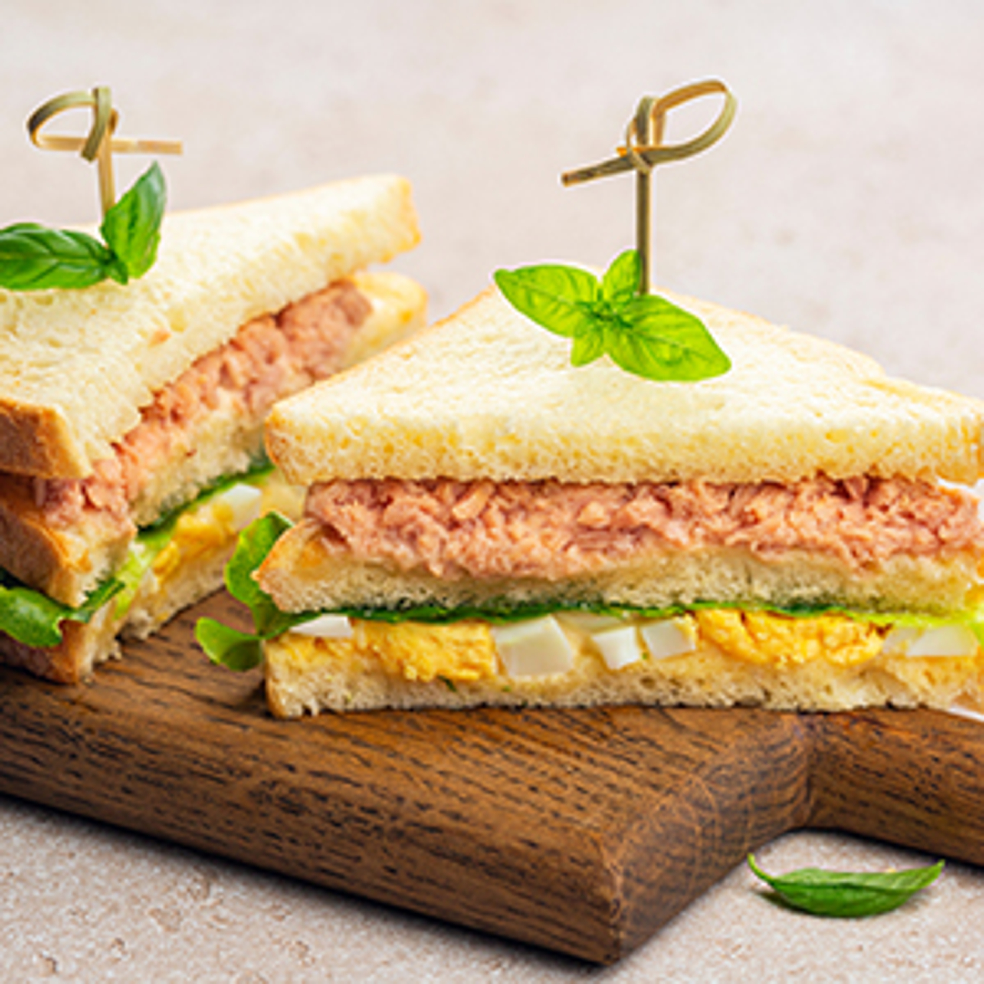 Breakfast fish with an egg salad and tuna sandwich on a board.