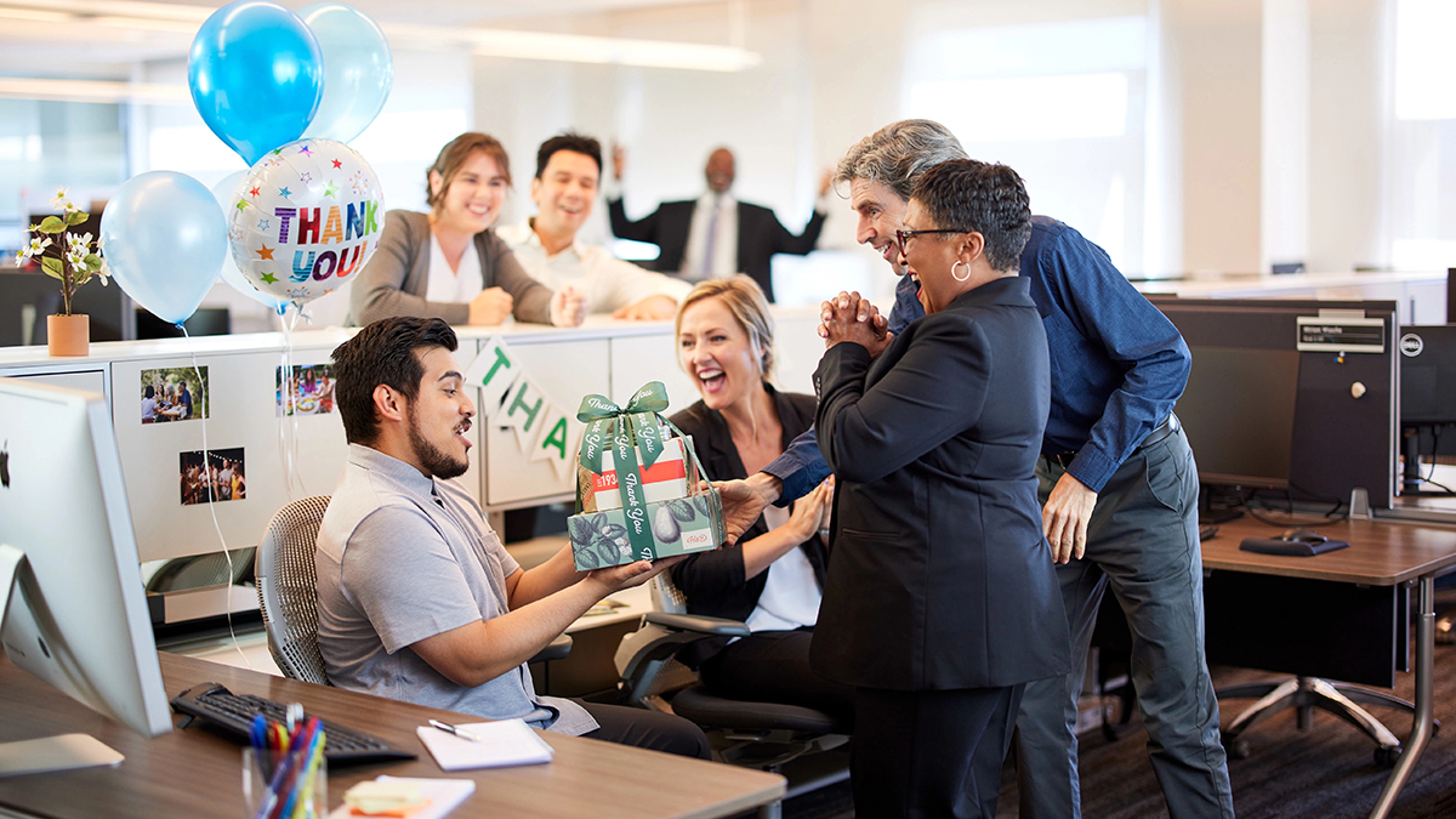 Employee appreciation days with a group of office workers giving someone a thank you gift.