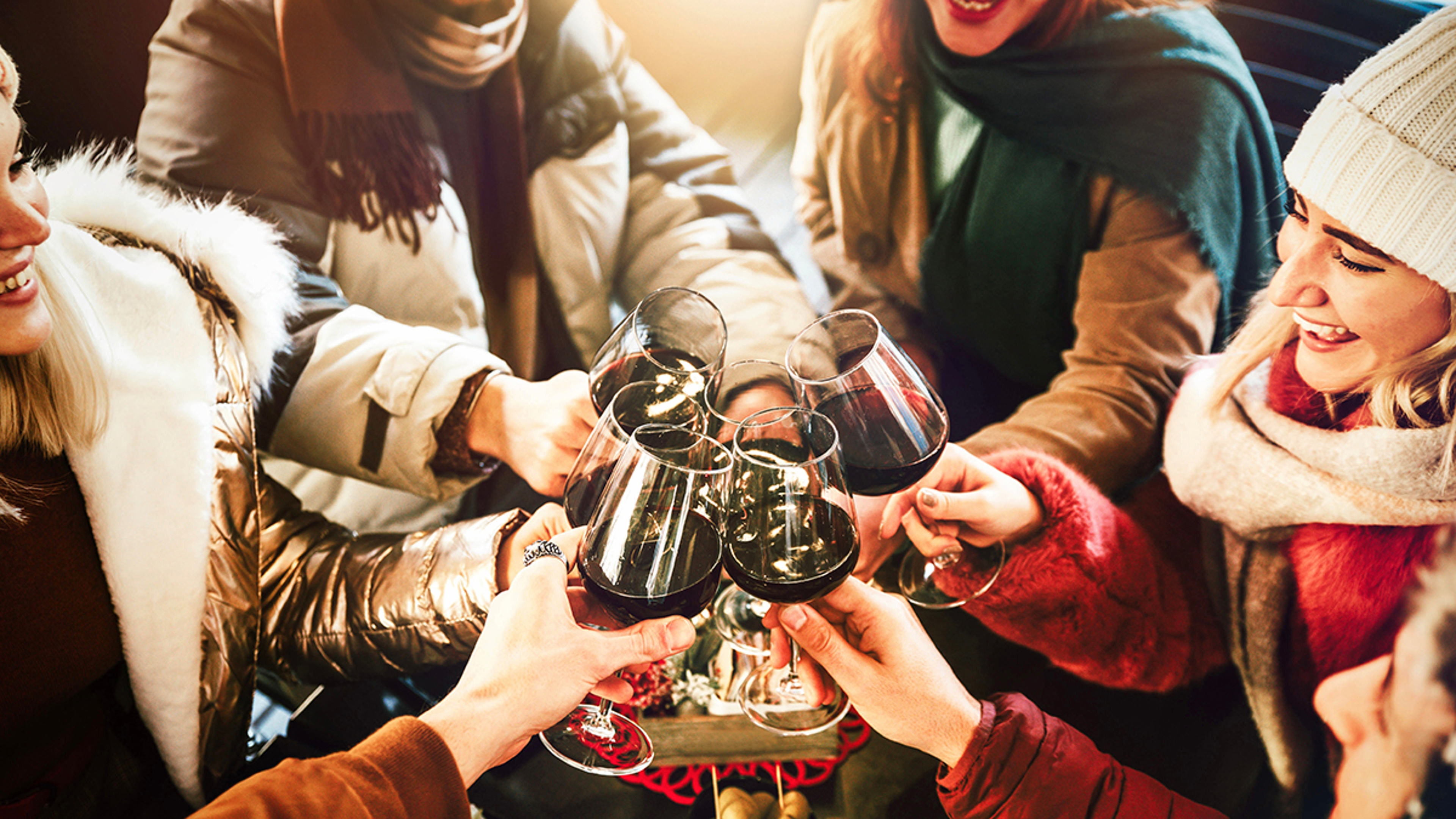 Happy friends group wearing winter clothes celebrating with red