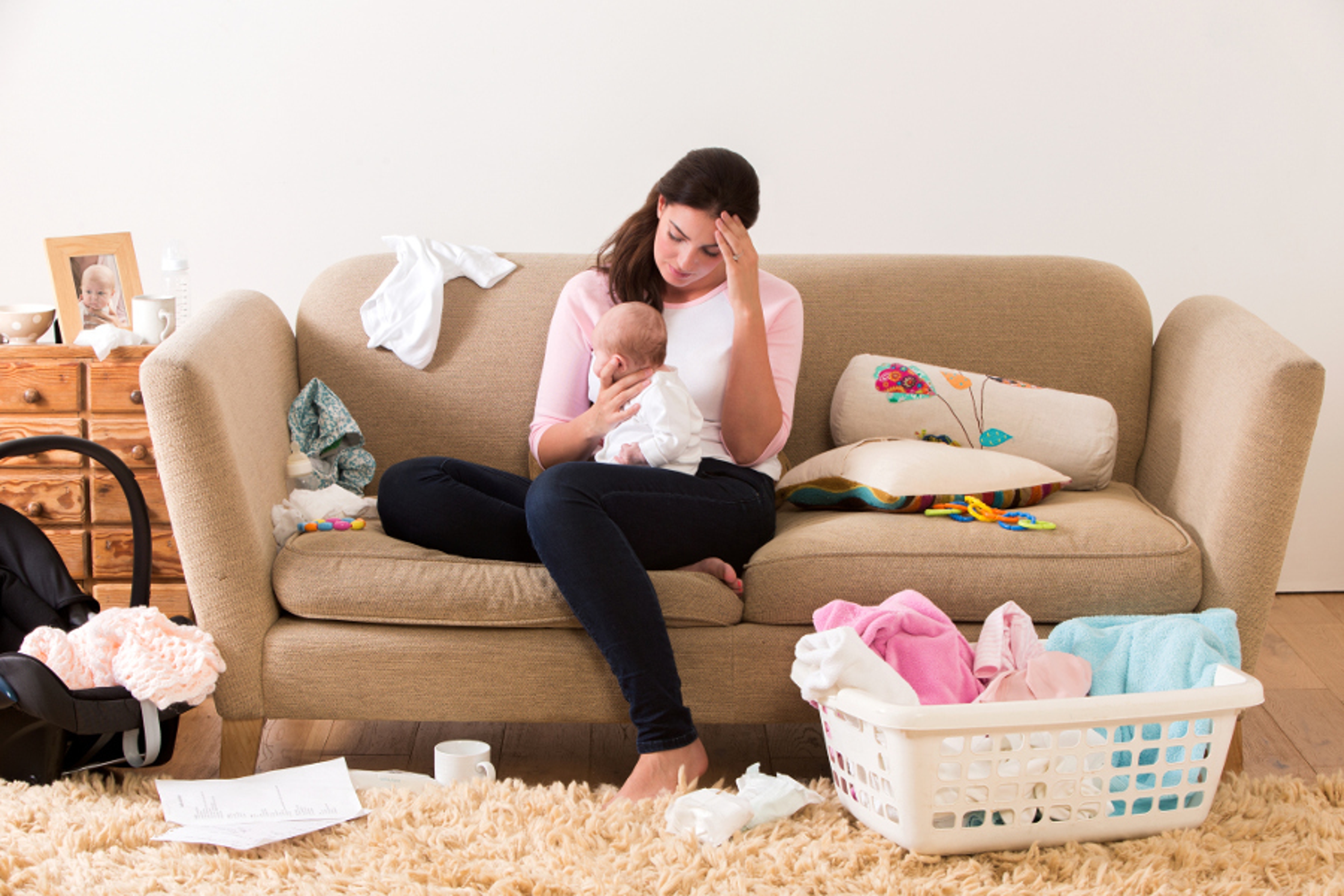 Article Cards Featured Image New parent mother sitting on couch with baby in lap, clothing and baby toys strewn about