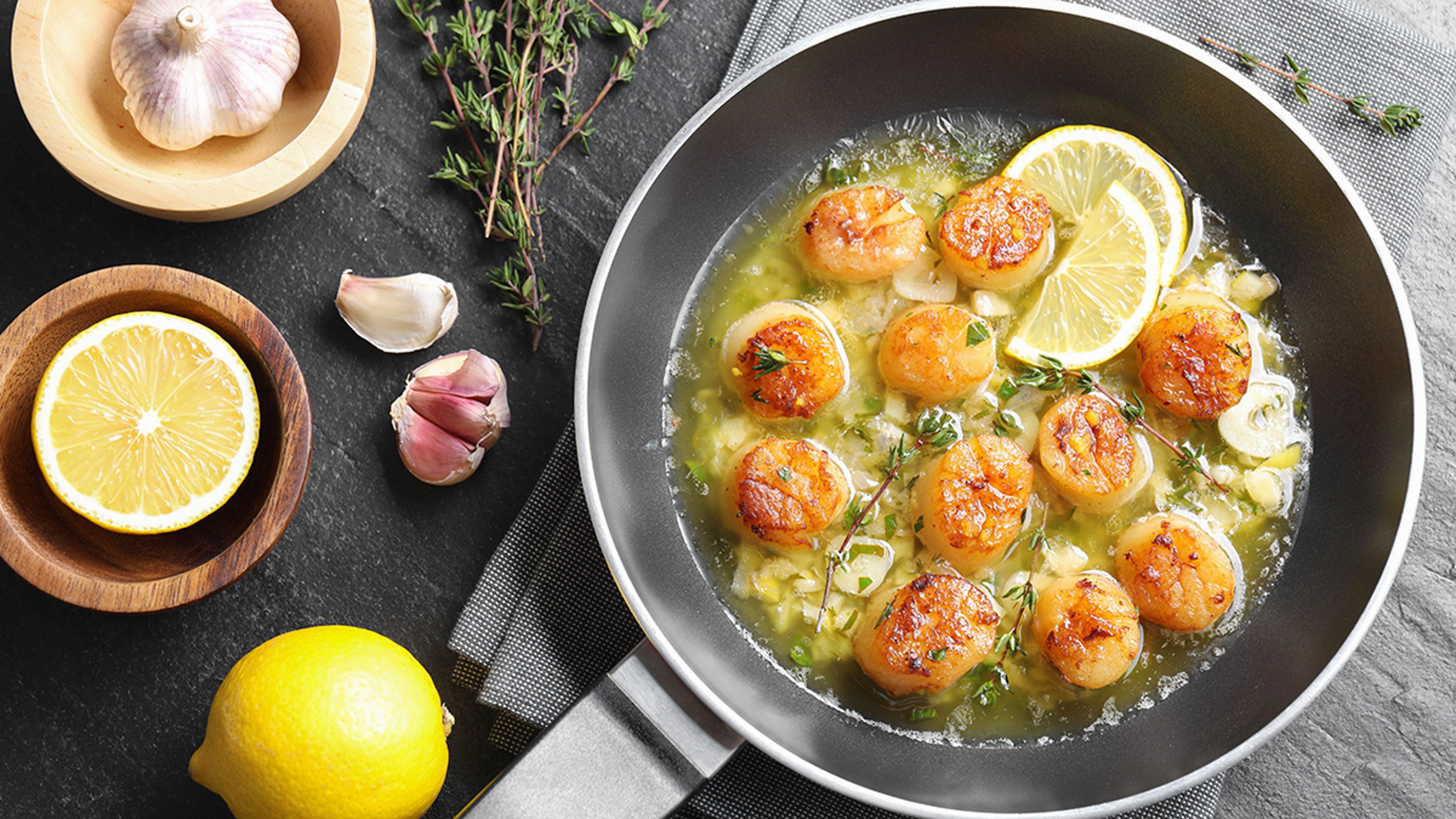 Pan of scallops cooked in butter, lemon, and herbs.