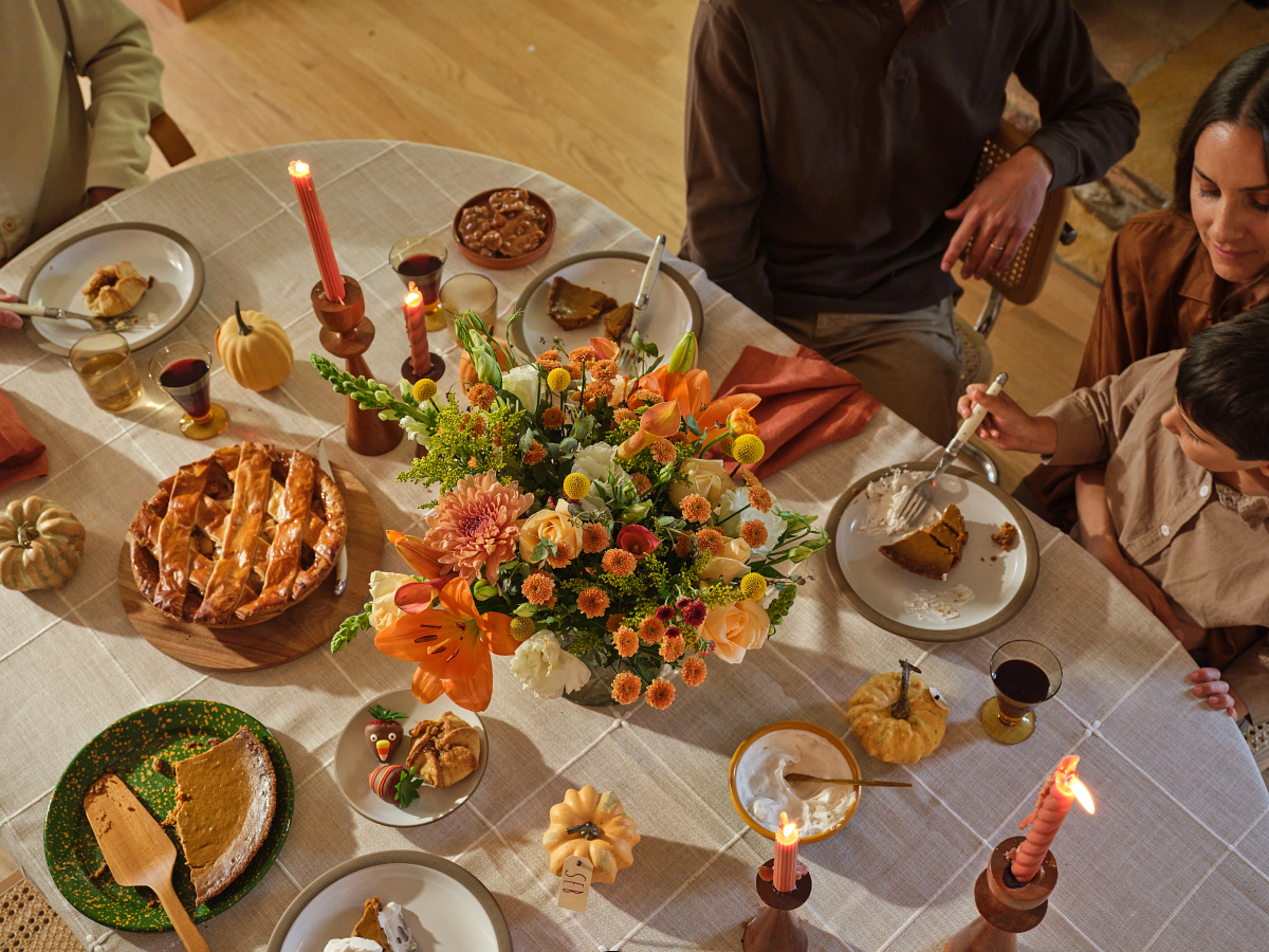 Overhead view of a Thanksgiving table laid with flowers and dessert.