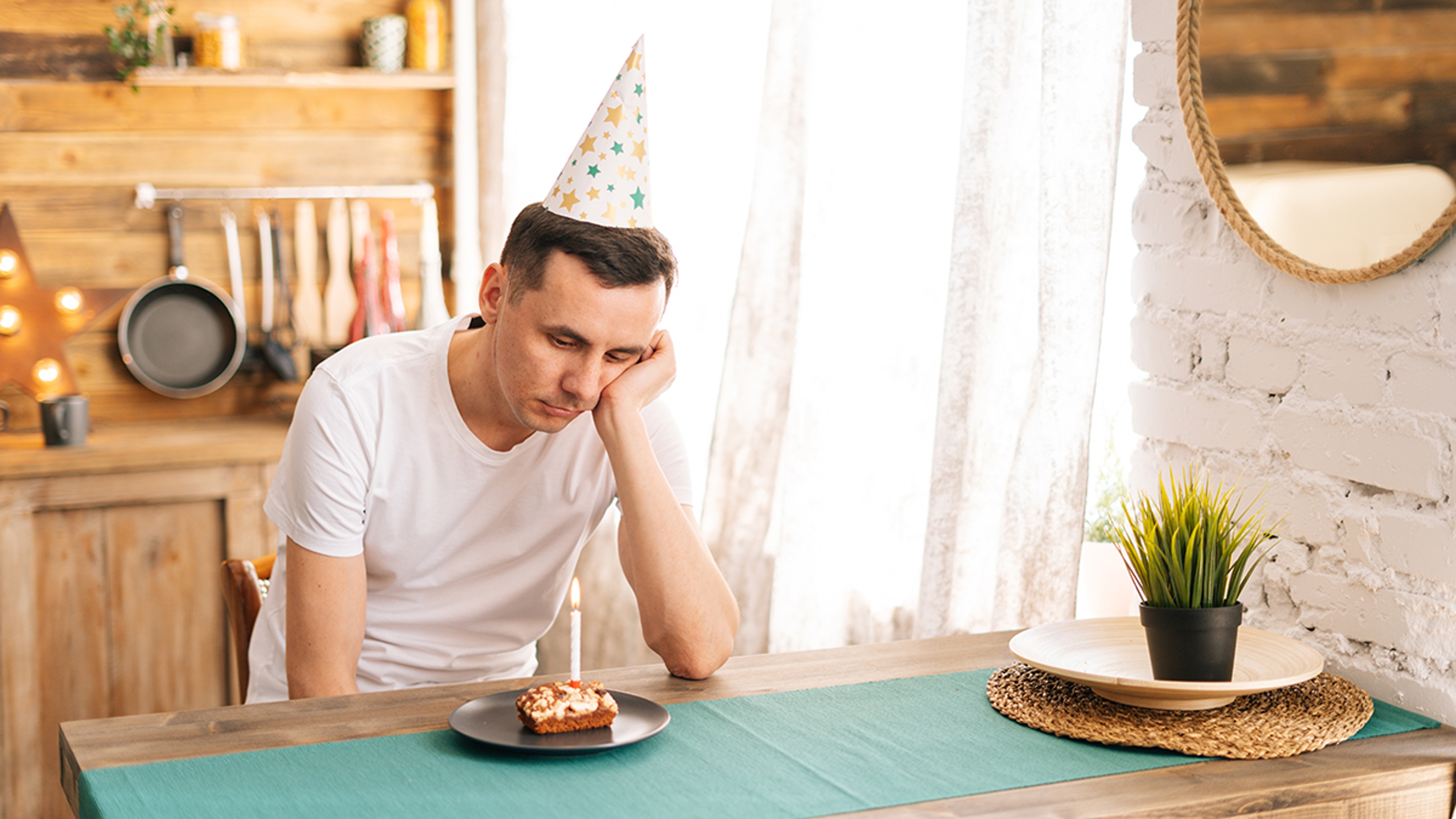 Article Cards Featured Image Upset young man sitting at the birthday cake and looking with sad eyes on it.