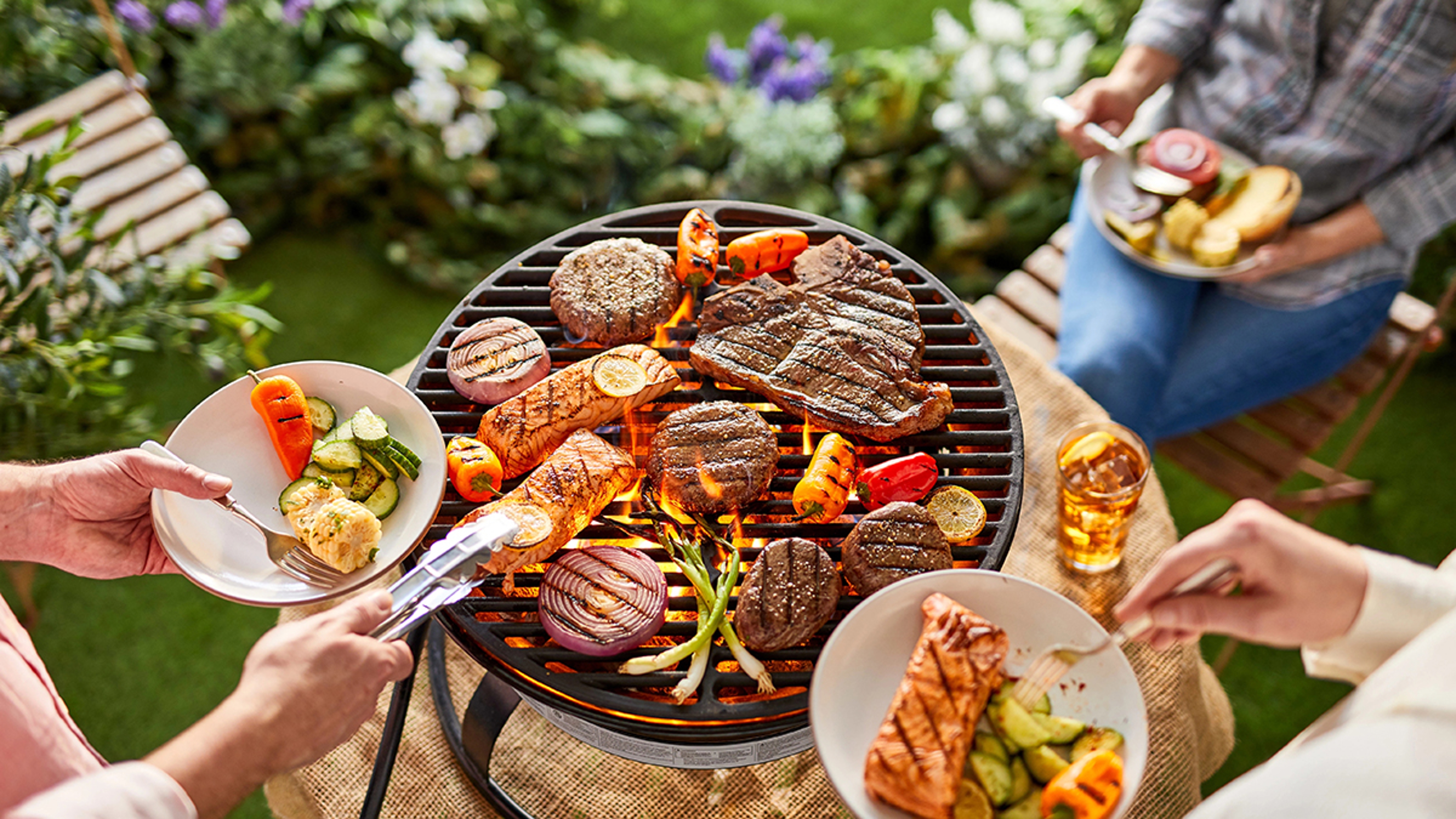 difference between grilling, barbecue, and smoking full grill with steaks, burgers, salmon, and vegetables.