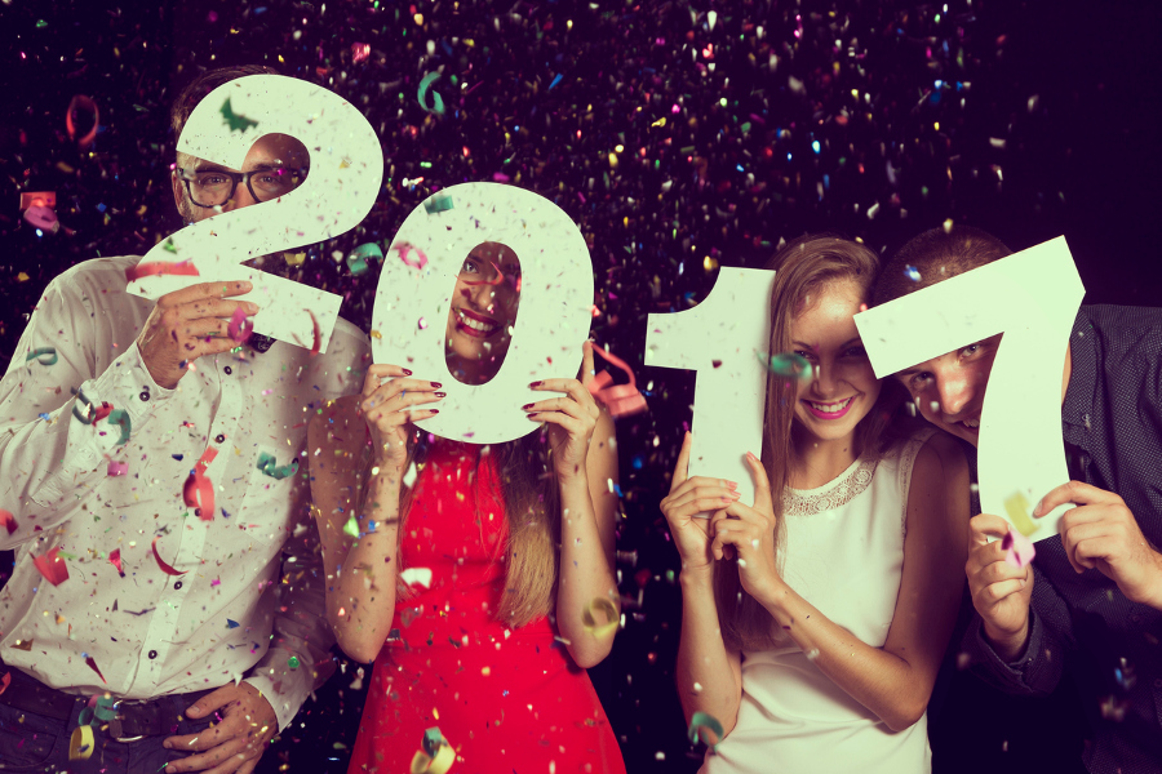 Article Cards Featured Image Two beautiful young couples having fun at New Year's Eve Party, holding cardboard numbers