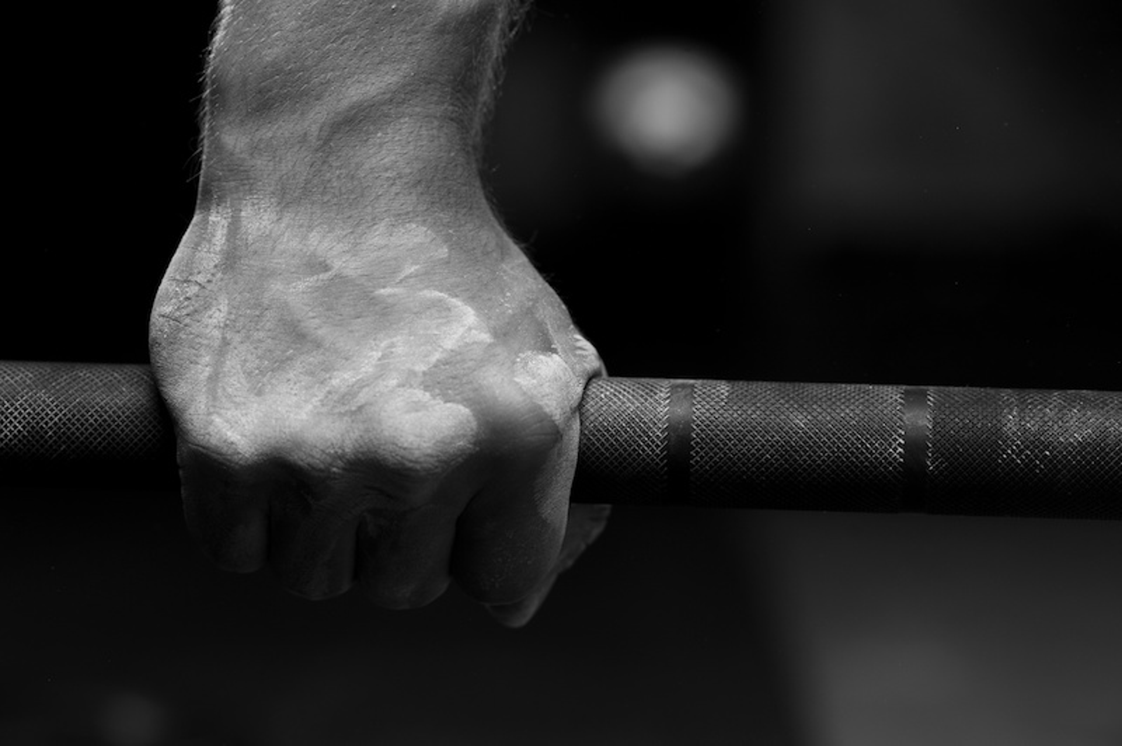 Article Cards Featured Image Closeup of male hand holding barbell, preparing to weightlifting or cross fit exercies.