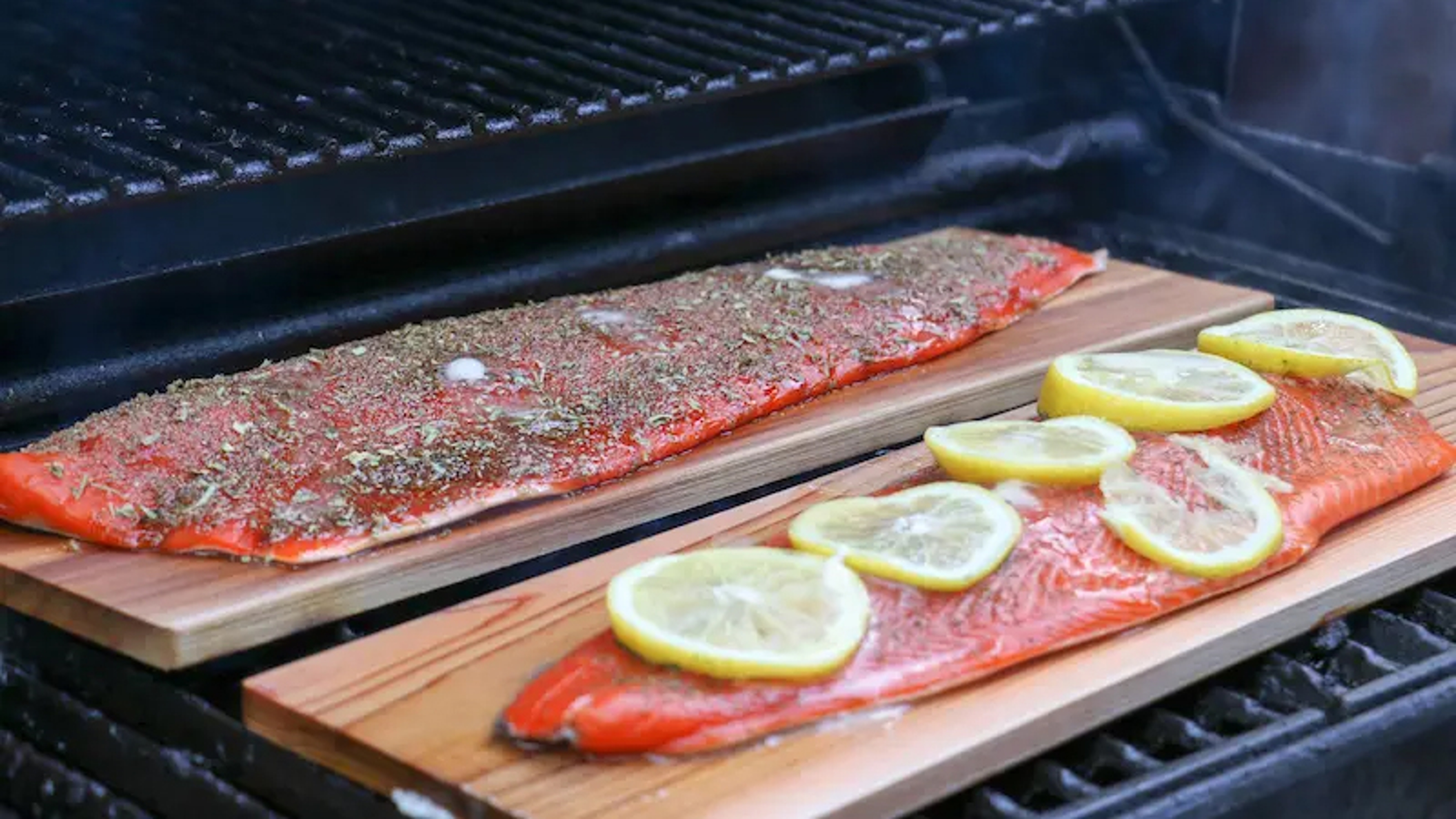 Salmon grilling on cedar planks on a grill.