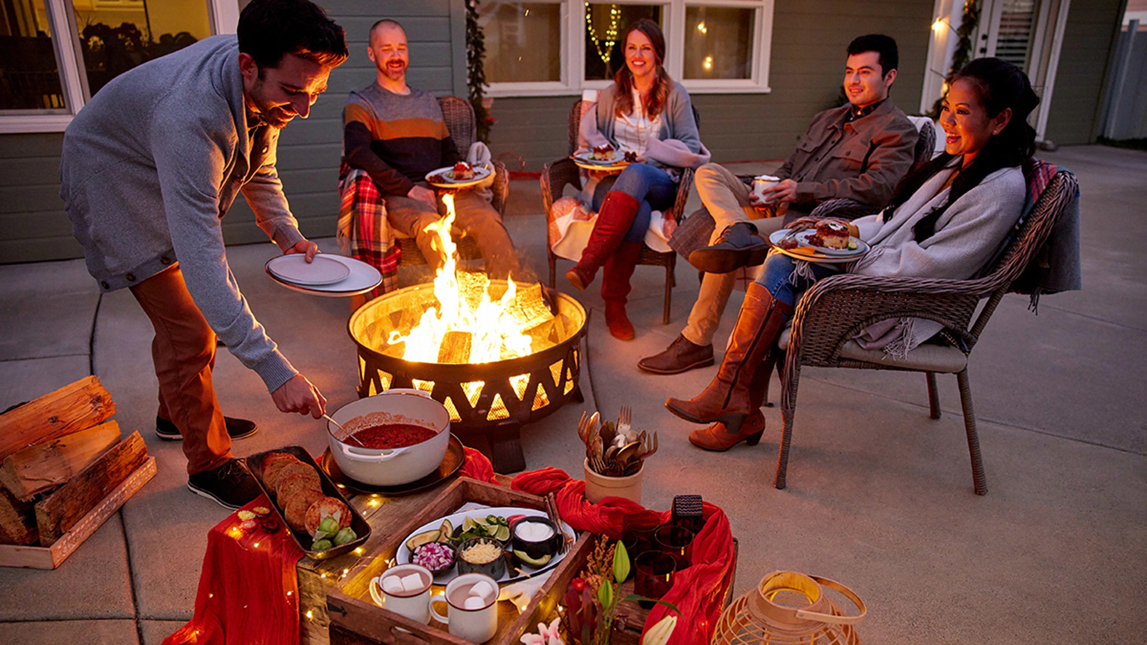 Adults celebrating a fall birthday with a bonfire outside.