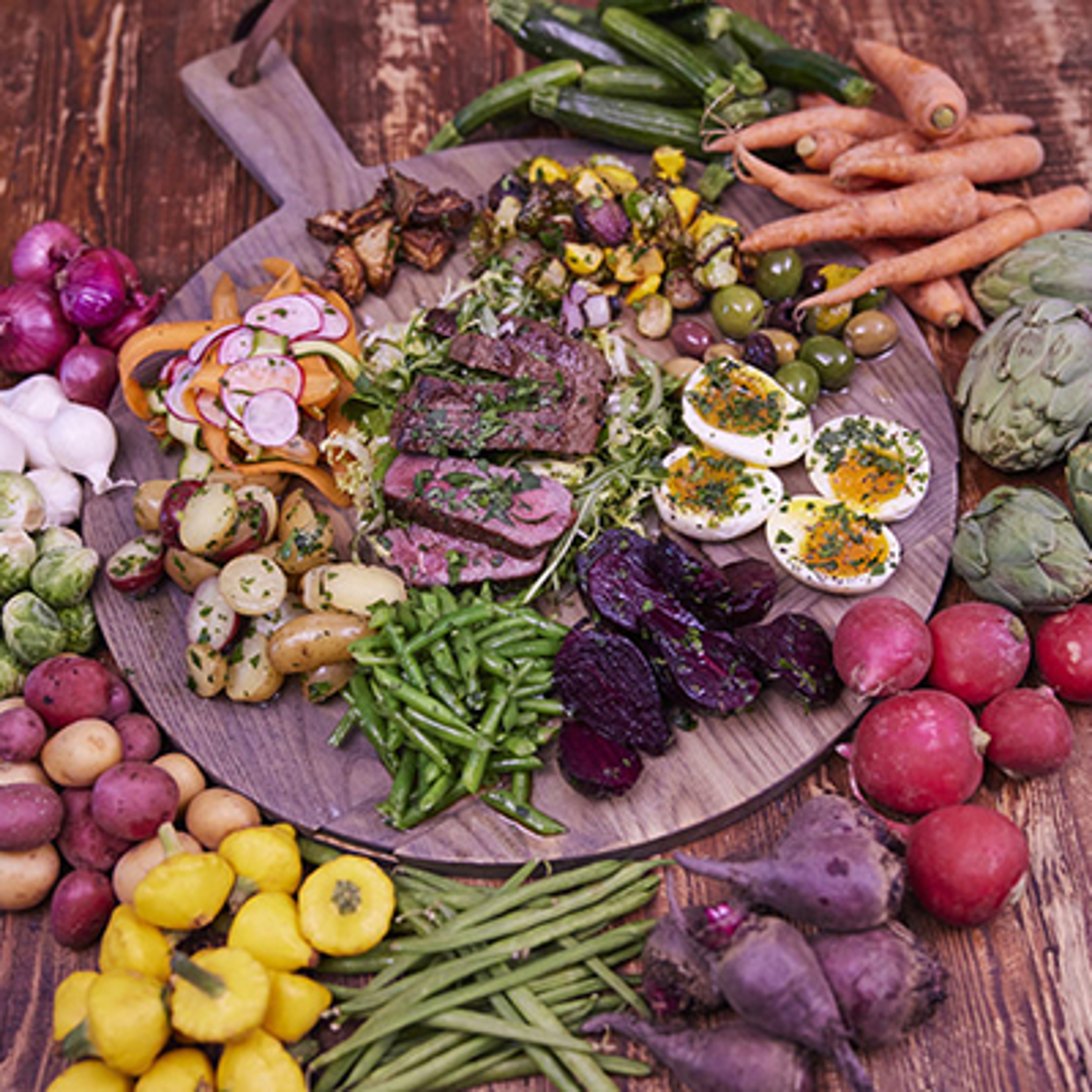 Steak salad on a board surrounded by fresh ingredients.