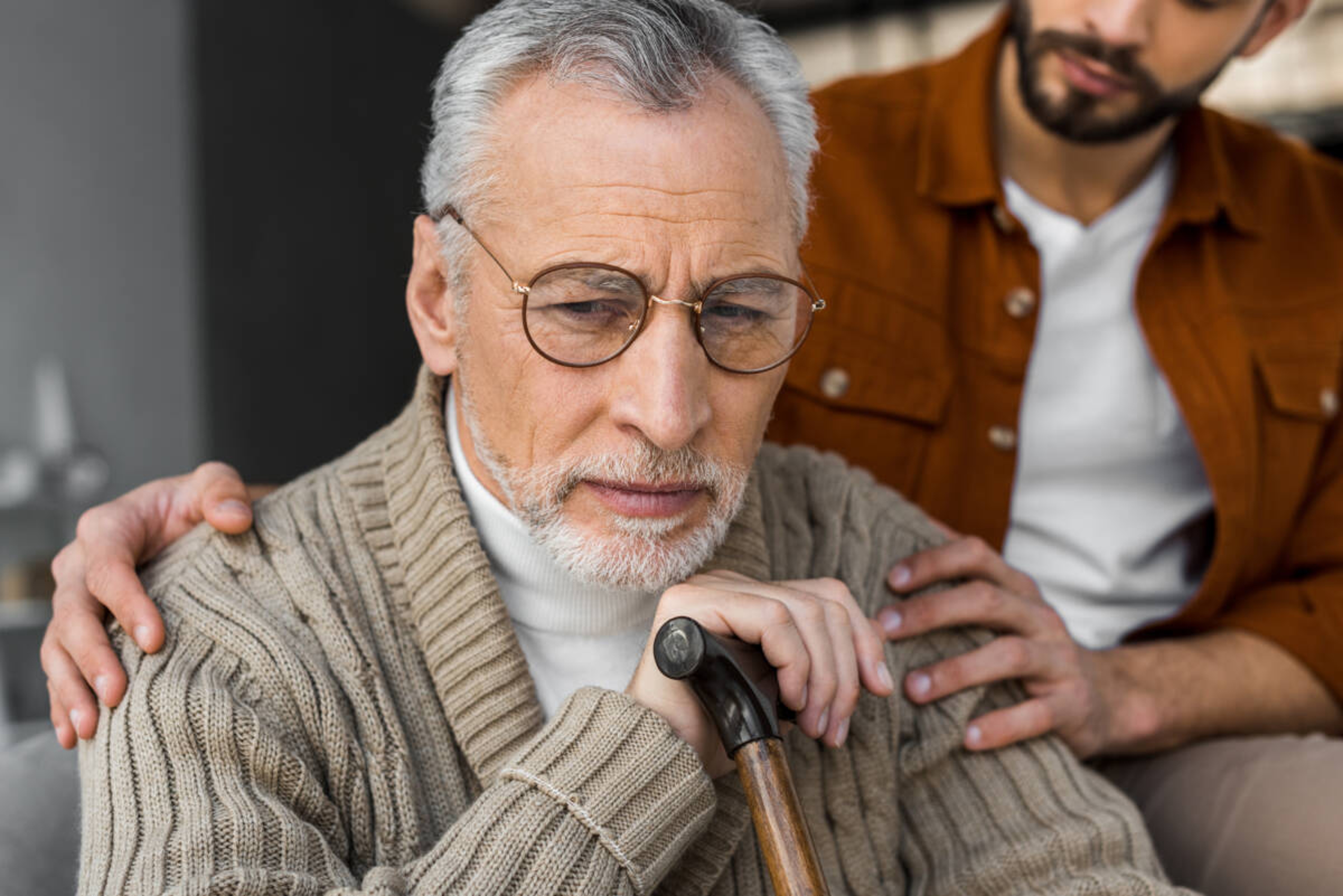 first year of loss with an older man holding. cane being consoled by a younger man.