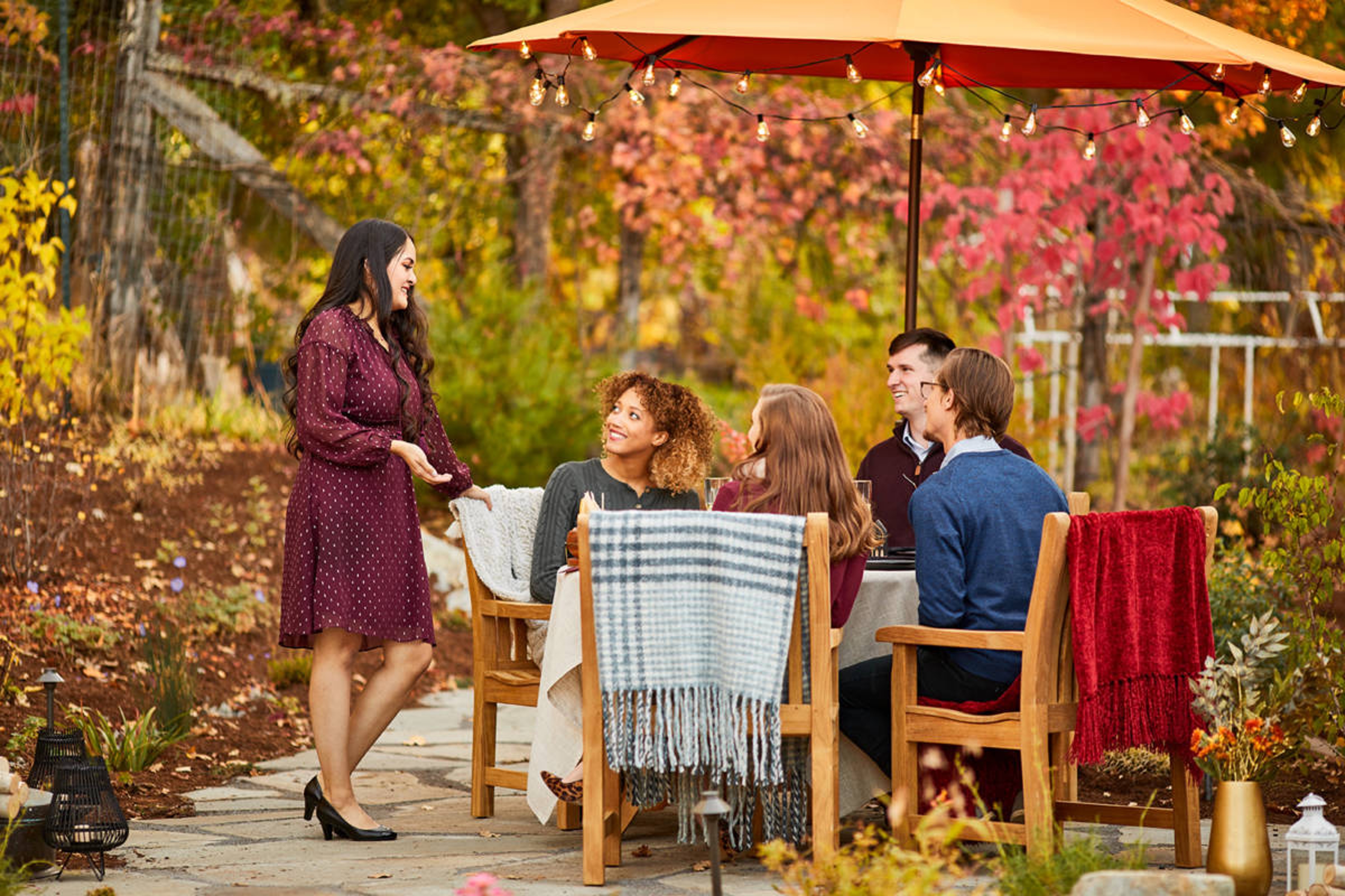 October birthday image group of people sitting outside at a table with fall leaves in the background