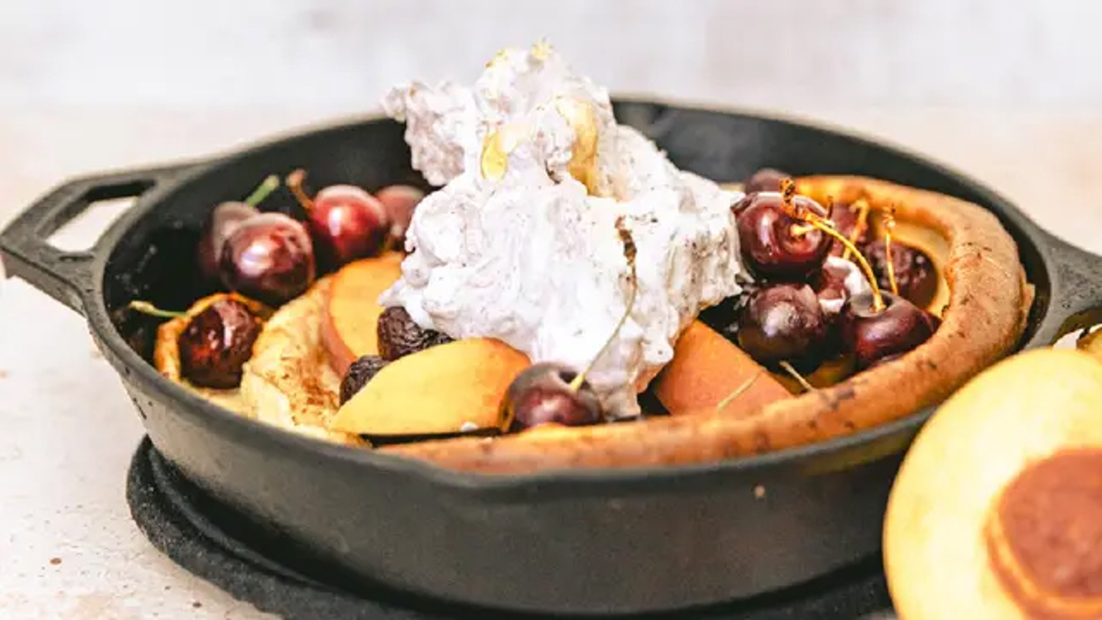 Breakfast ideas with a cast iron skillet holding a Dutch baby pancake topped with fruit.