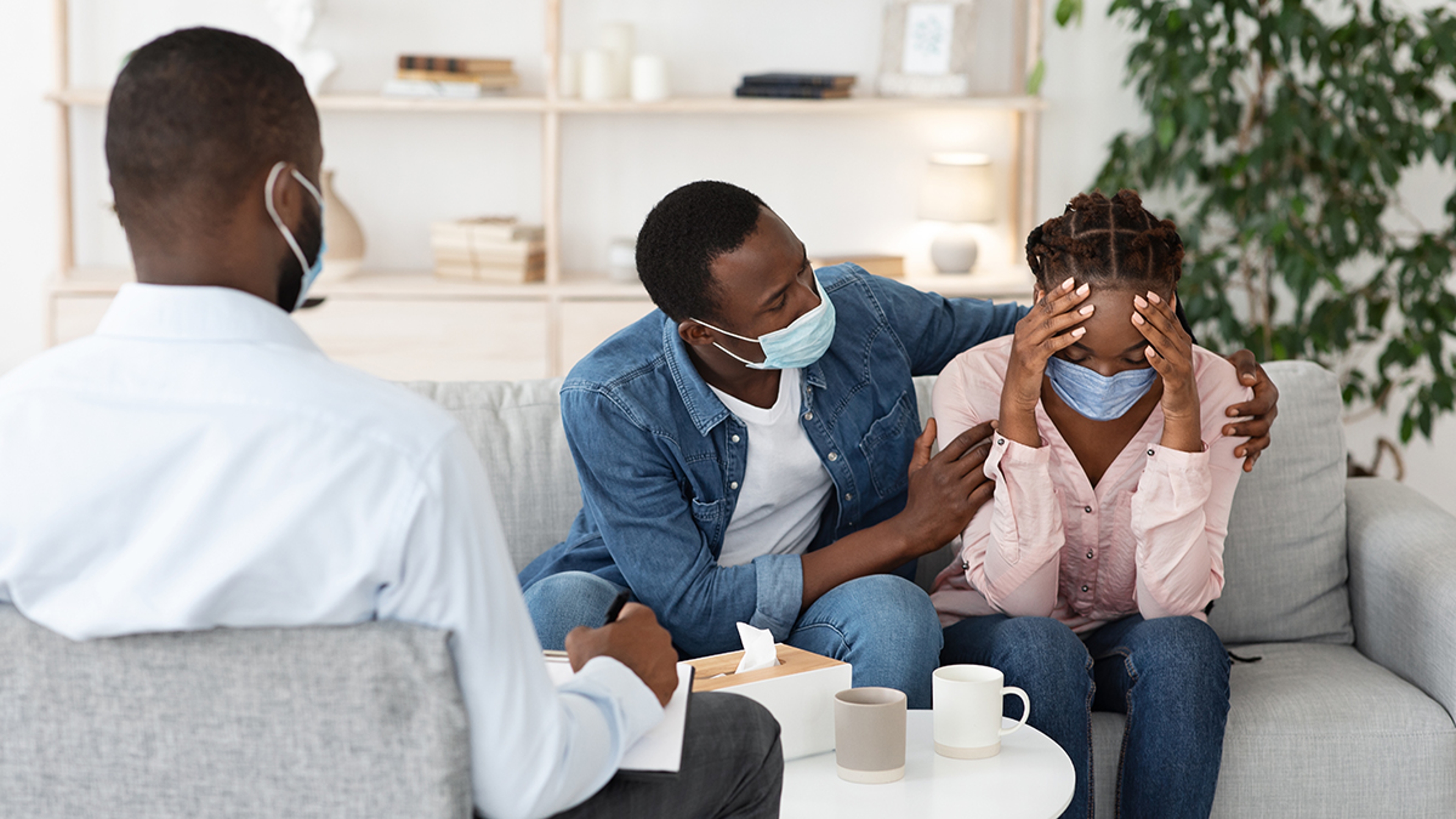 Caring Husband Comforting Wife Having Mental Health Problems After Coronavirus, Sitting At Therapist Office Together