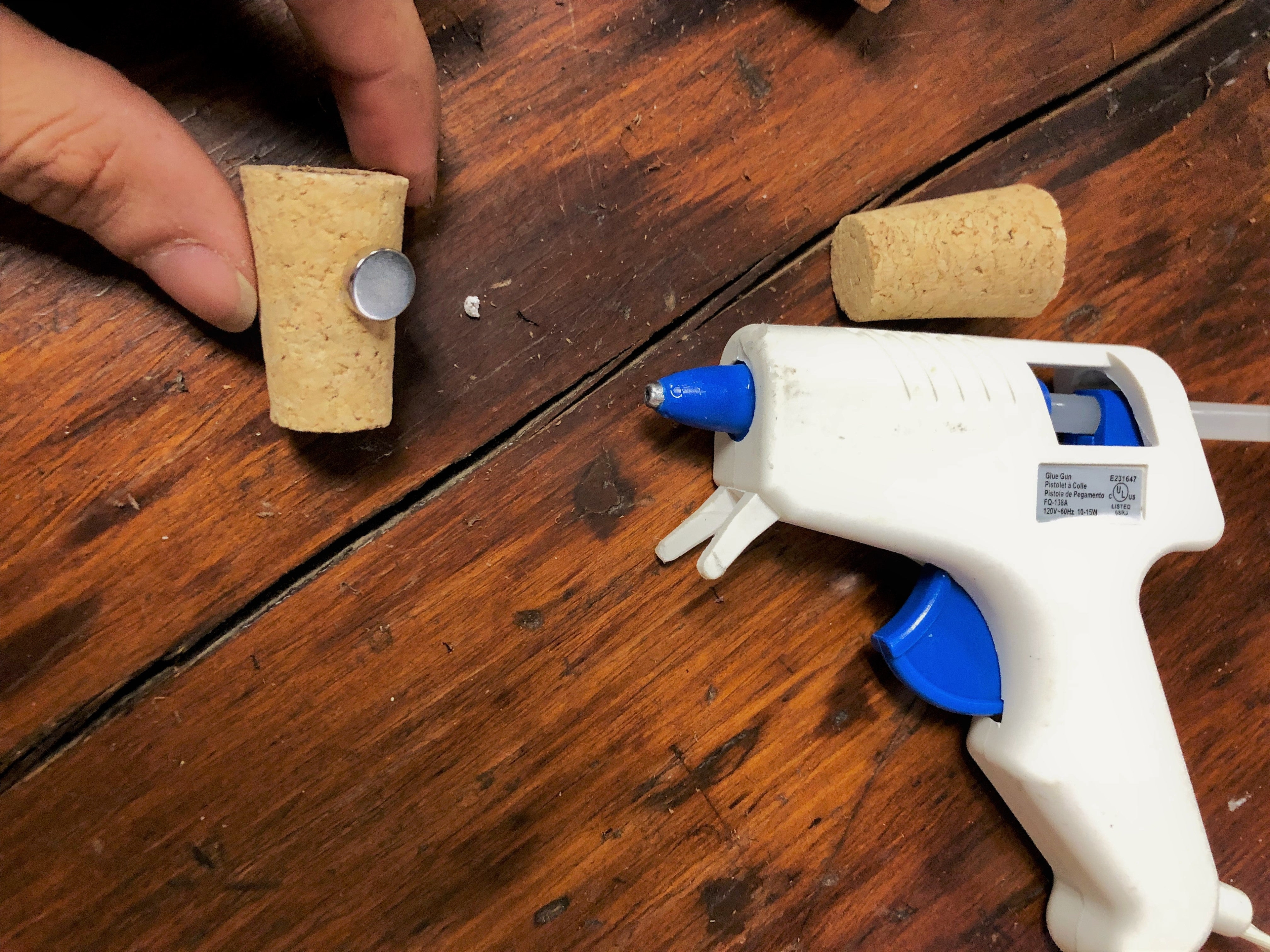 Using a hot glue gun to attach the magnet to the cork