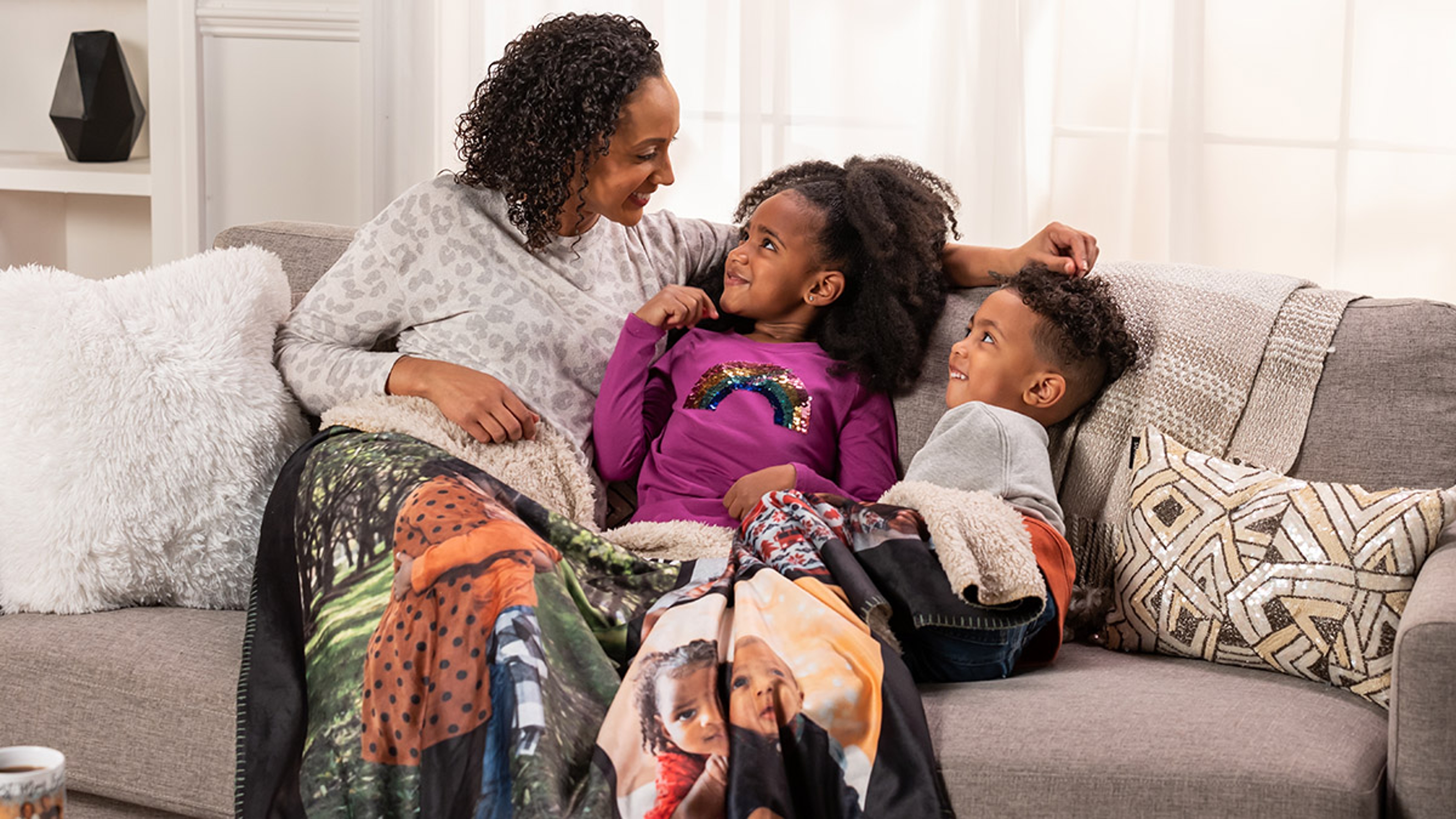 Motherhoood quotes with a mom and two kids snuggled under a blanket.