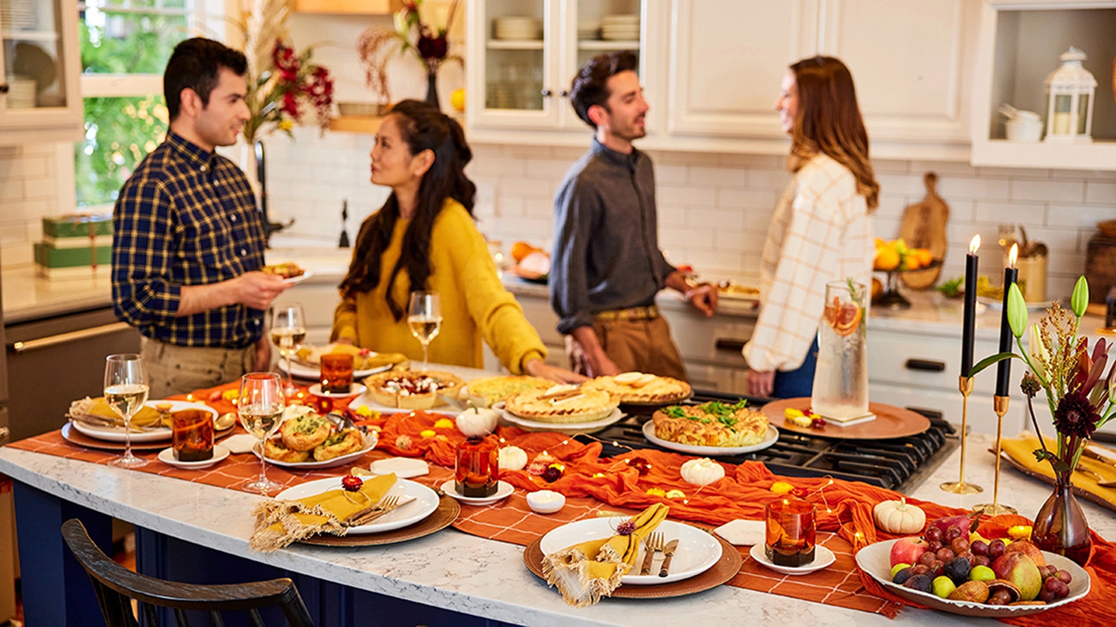 Group talking in a kitchen next to a table laid with food.