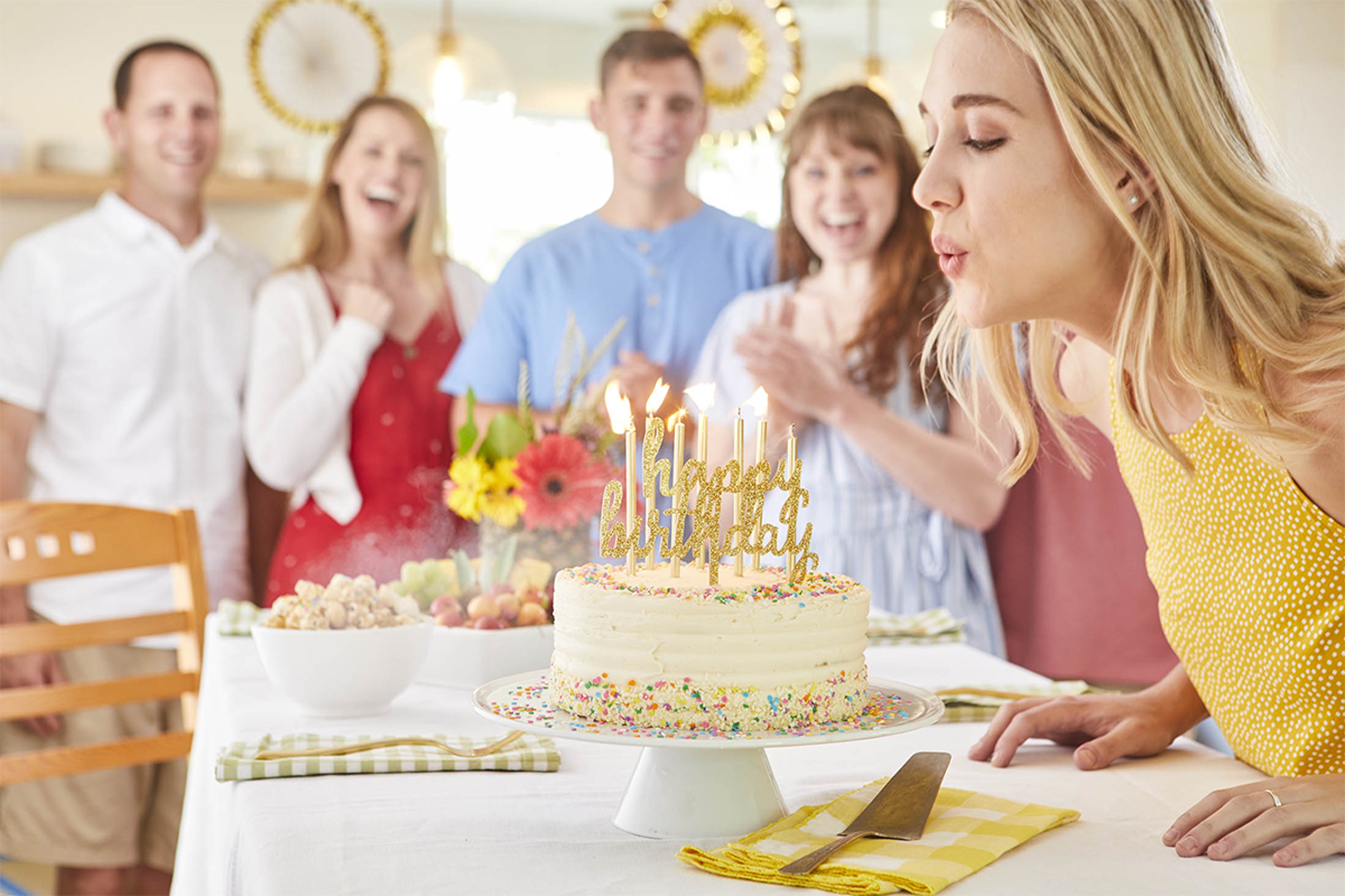 Woman blowing out candles at a milestone birthday celebration.