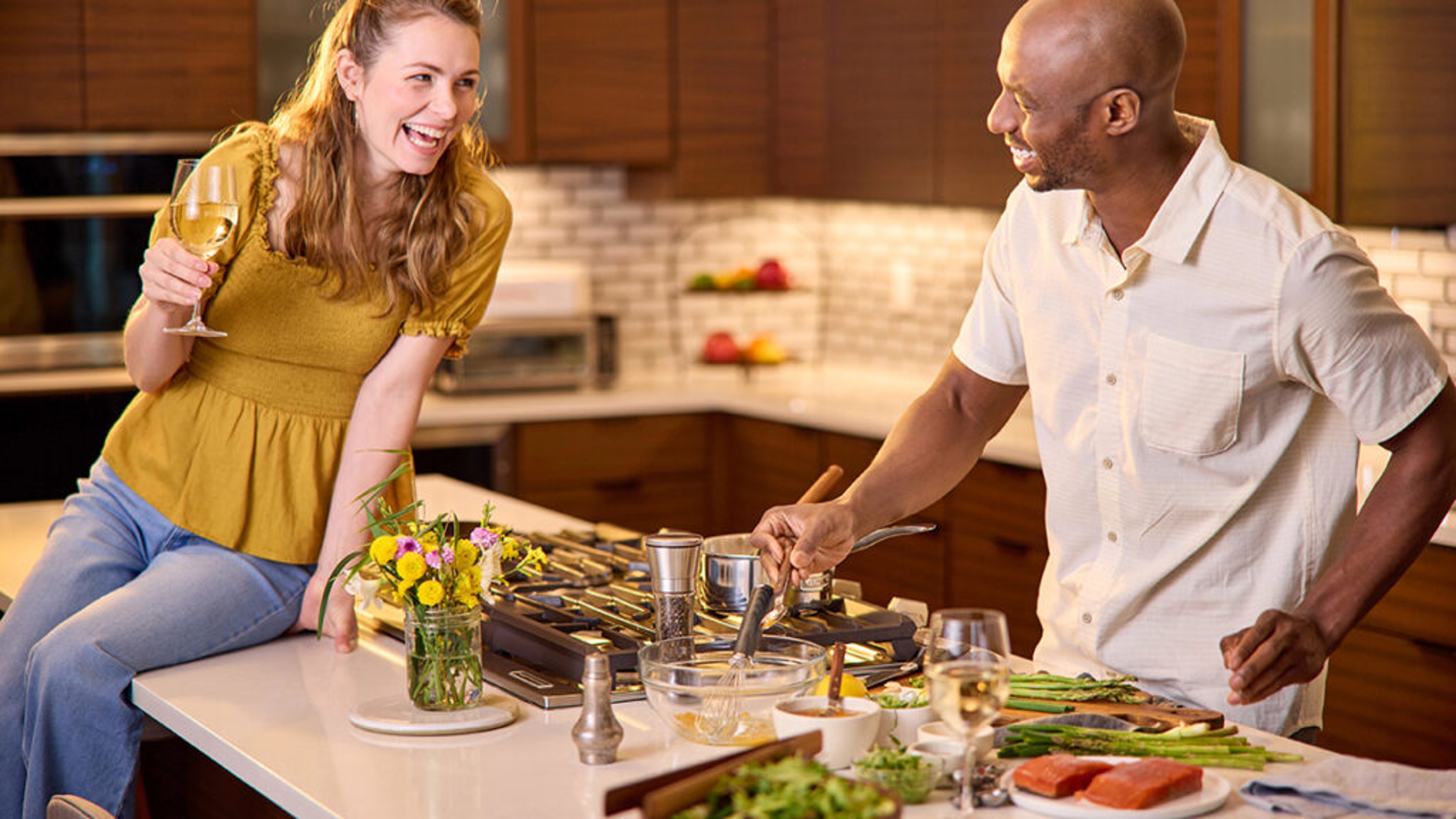 Couple cooking fish in a large kitchen.