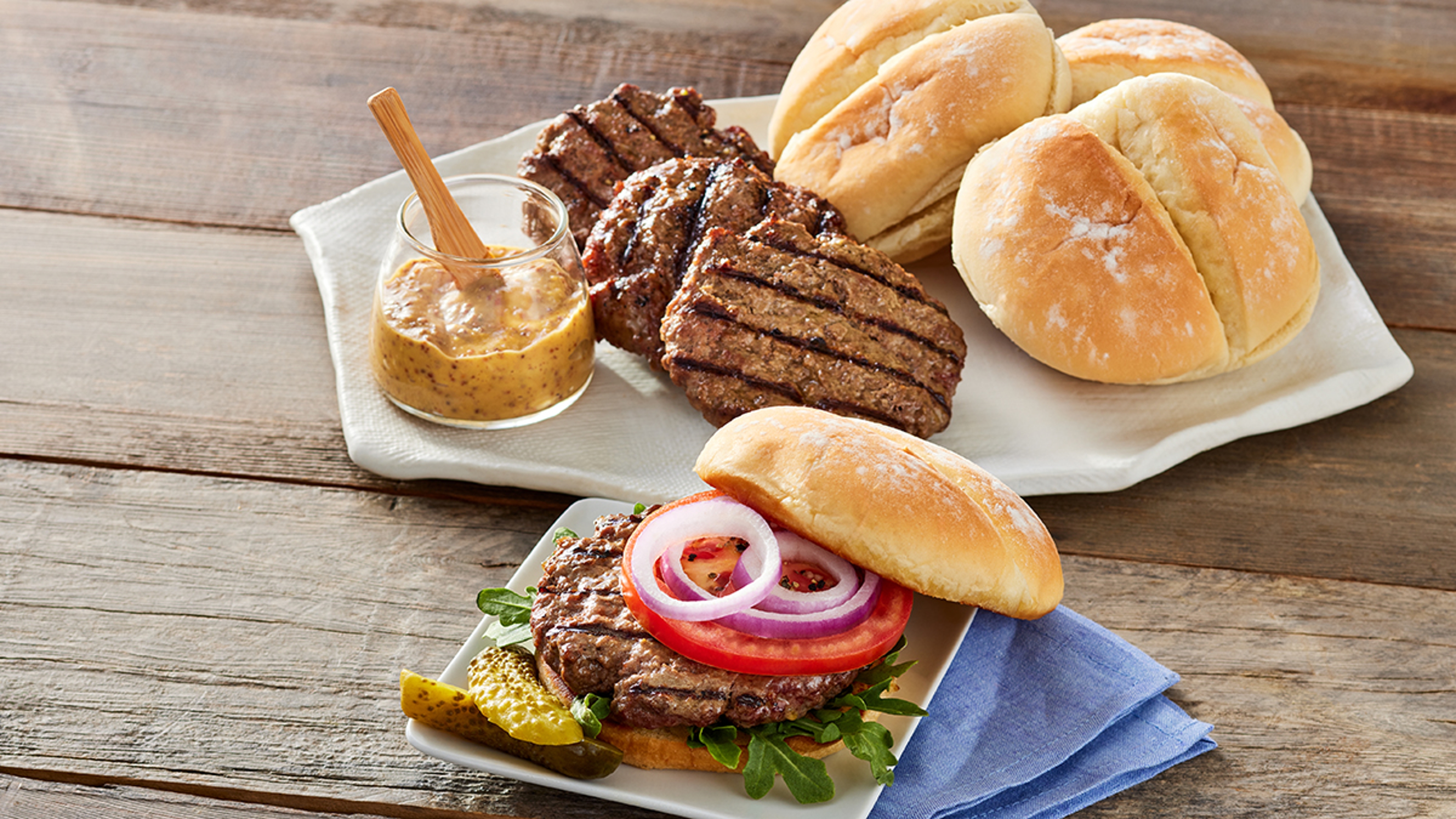 Bison burgers and condiments on plates.