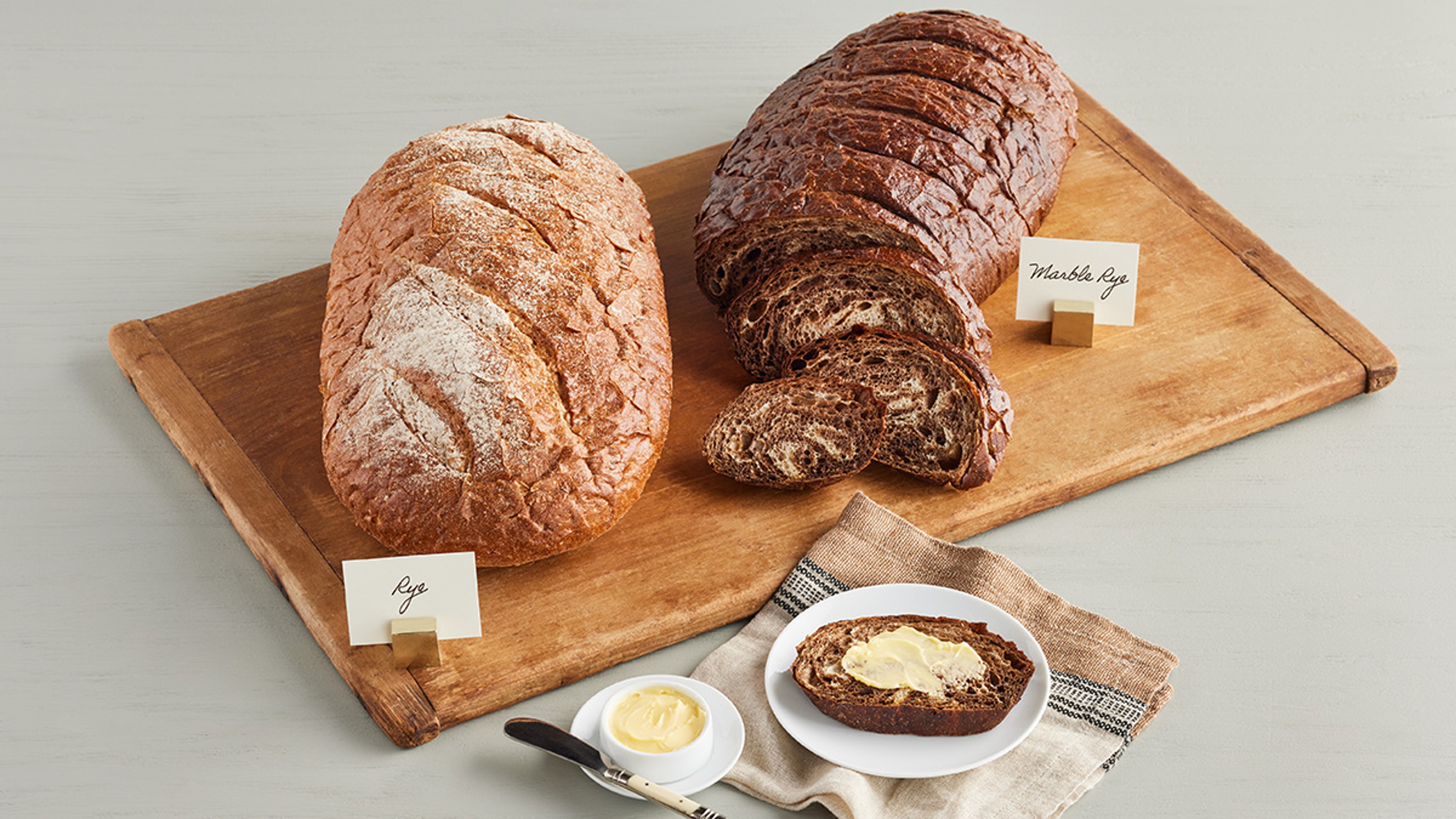 Two loaves of rye bread on a cutting board.