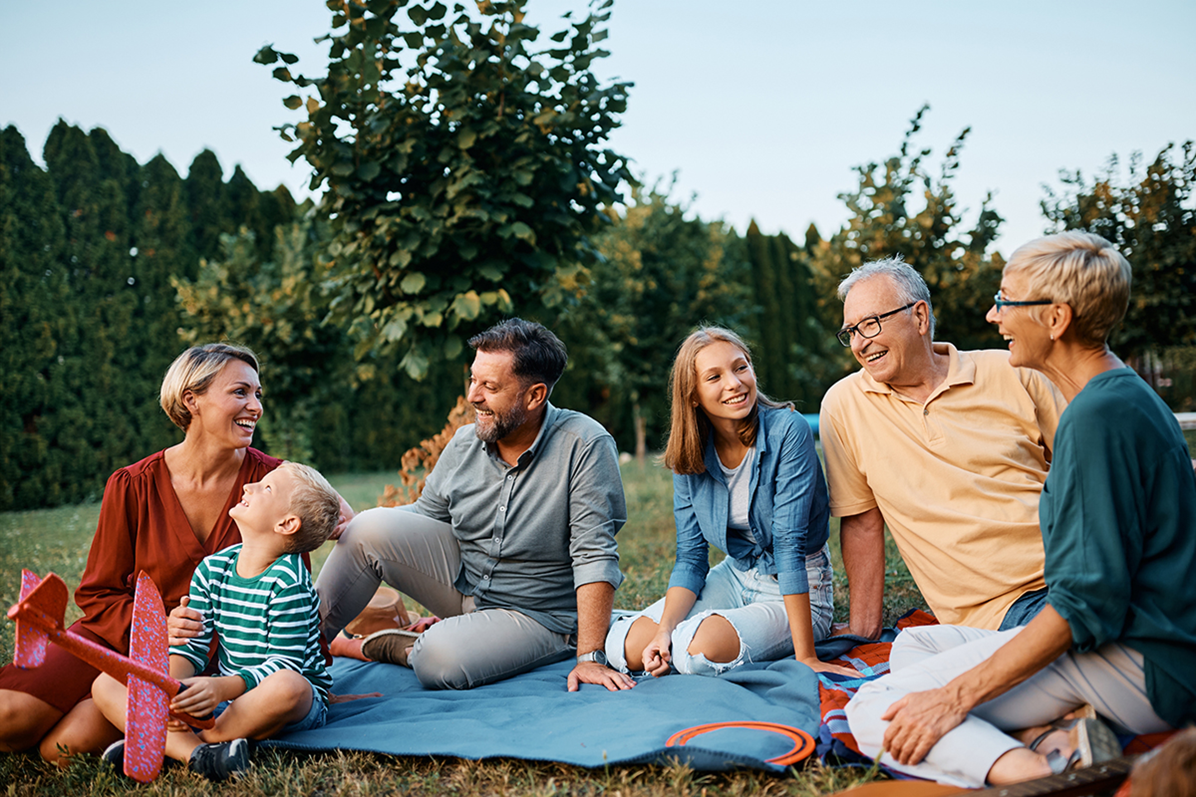 Article Cards Featured Image Happy multigeneration family talks while relaxing in backyard.