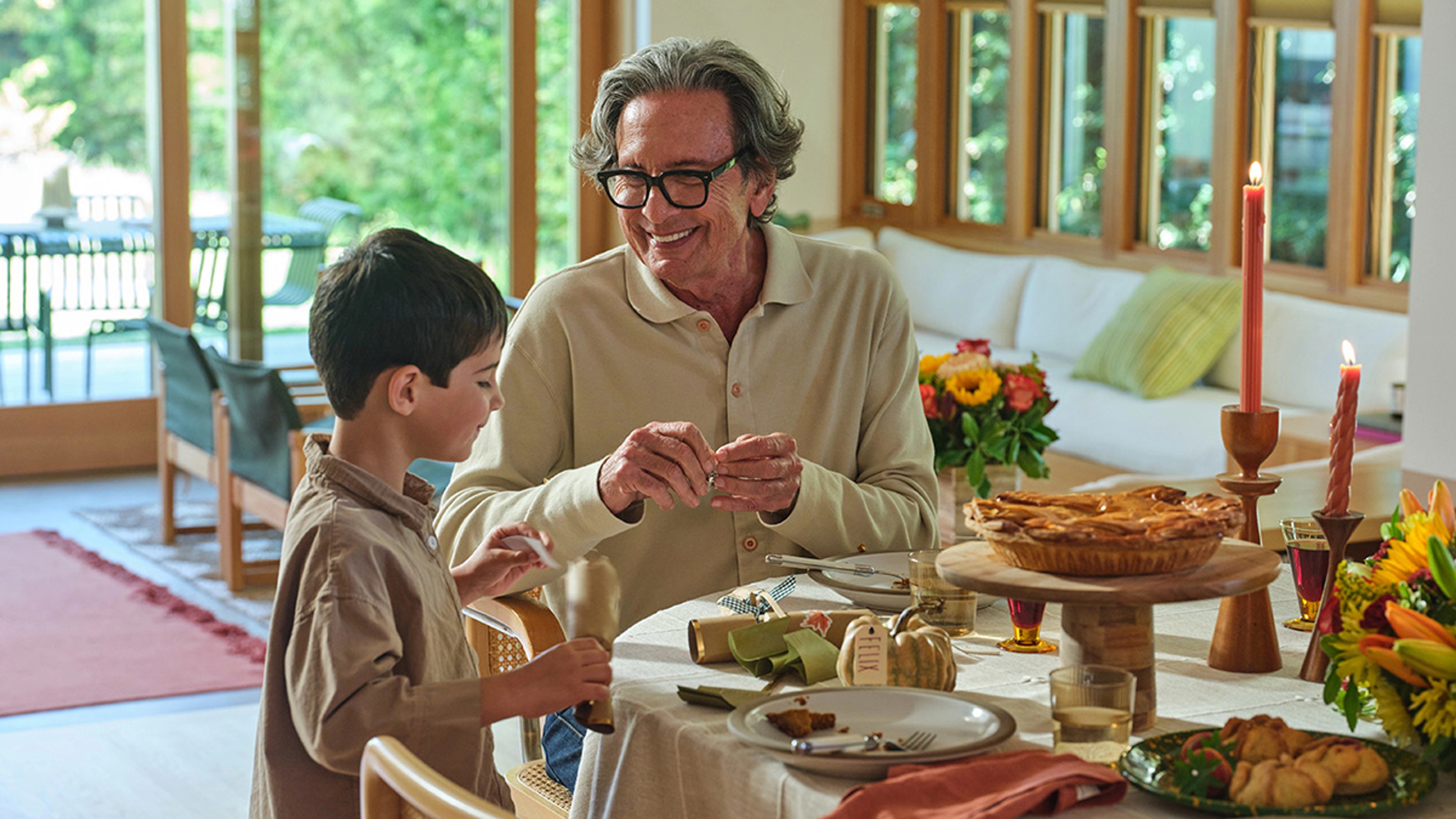 Grandparent helping grandson decorate a fall table.