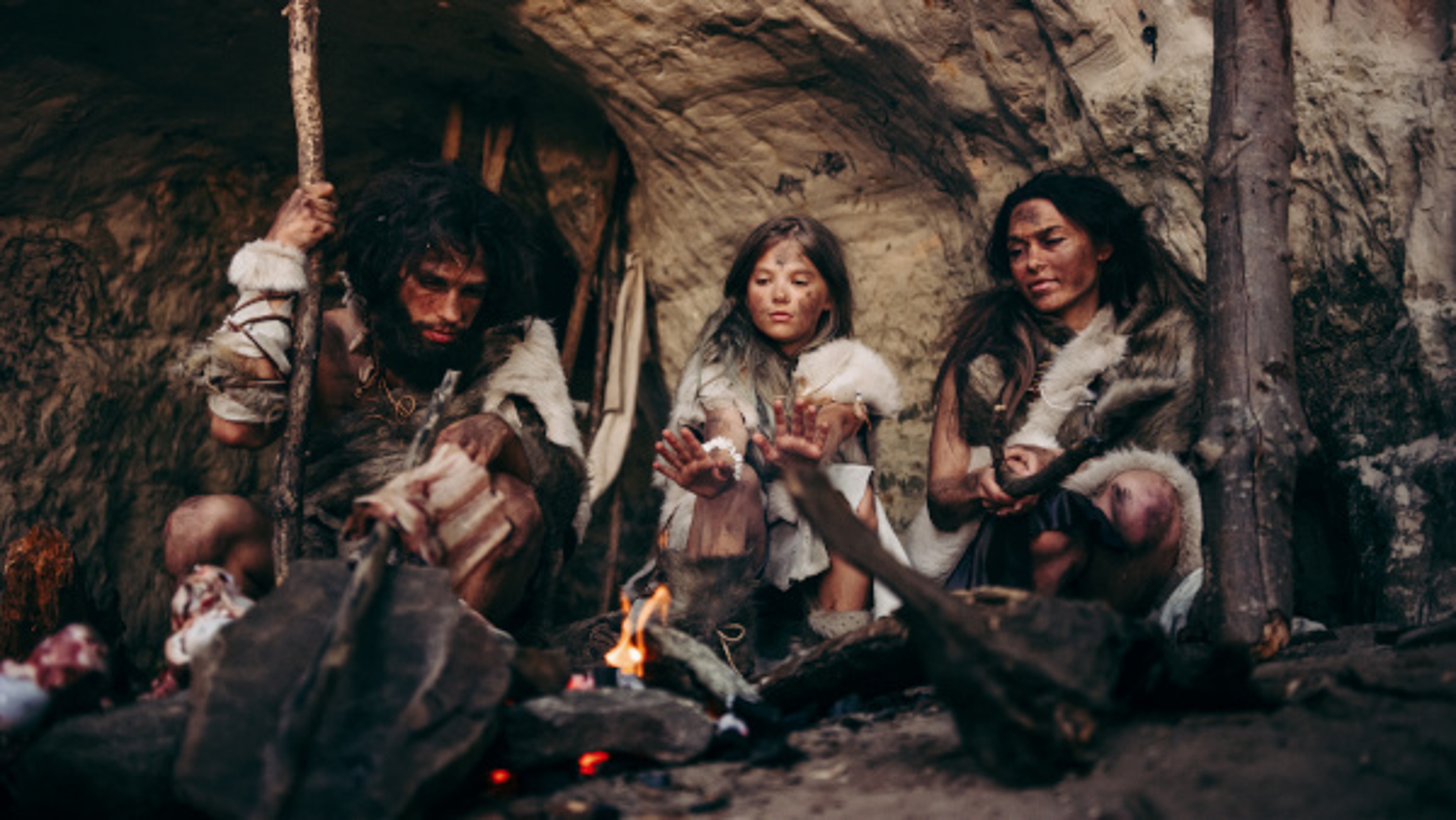 A photo of gift history with a group of cave people circle around a fire.A photo of gift history with a group of cave people circle around a fire.