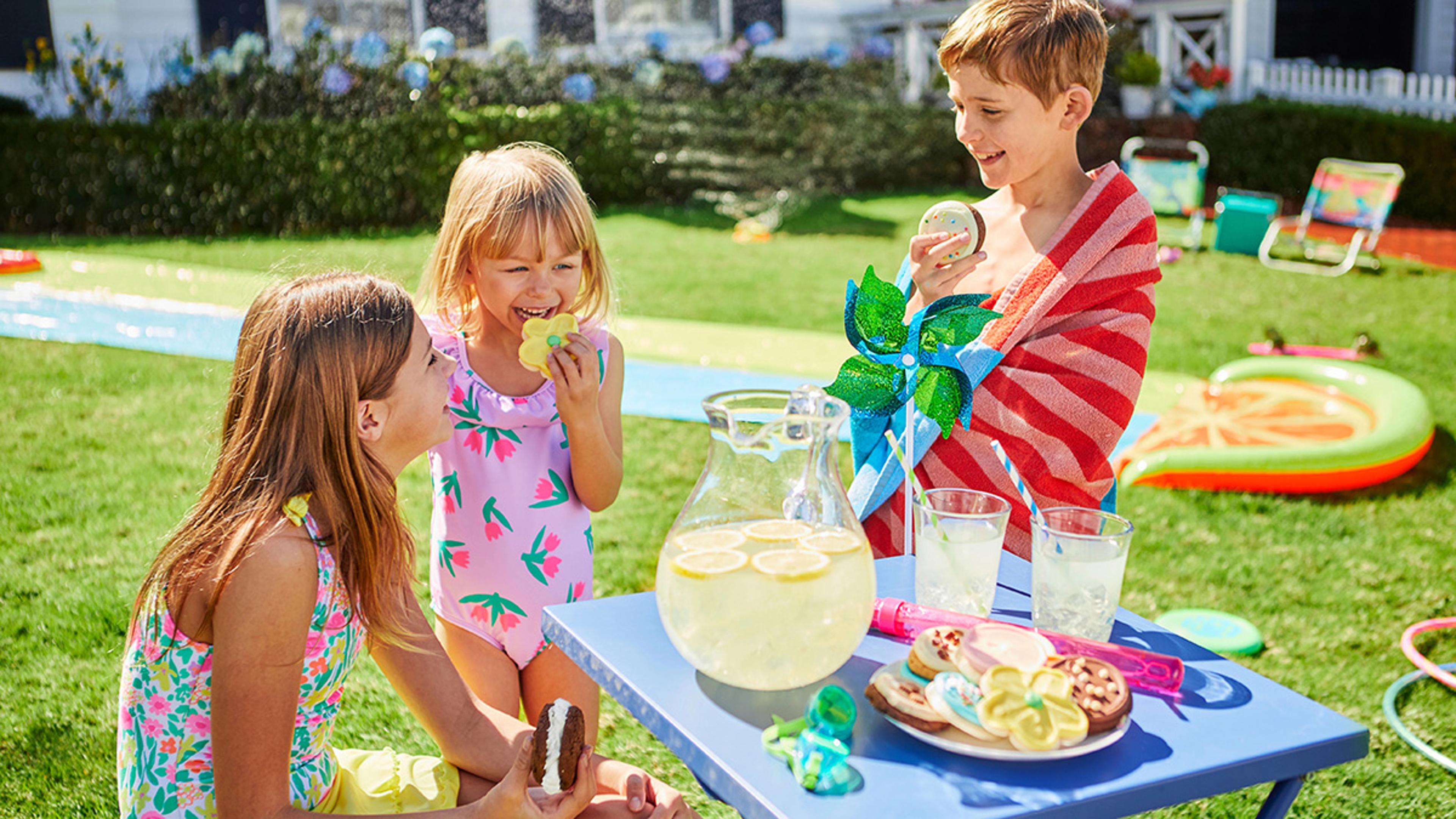 Kids celebrating a summer birthday with a slip & slide, cookies, and lemonade.