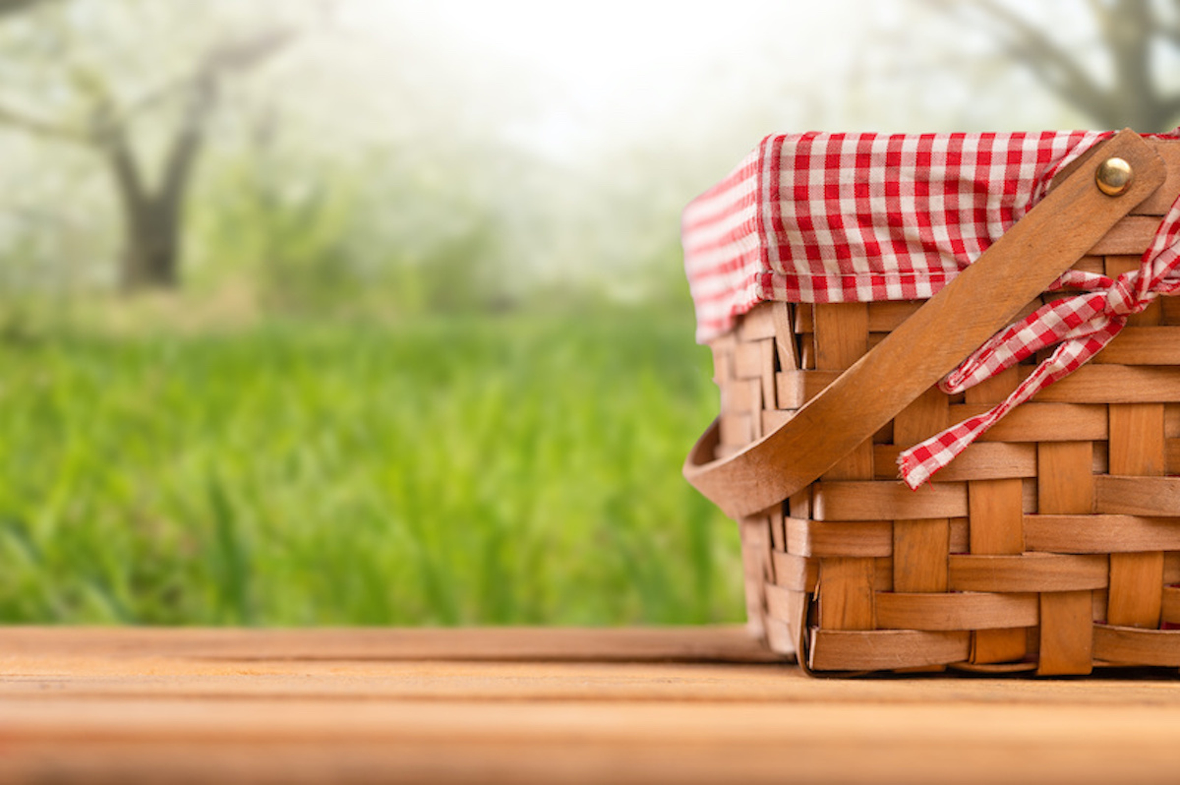 Article Cards Featured Image Picnic basket on a wooden table, against the backdrop of the landscape. Rest and picnic. Weekend or vacation. Concept of summer mood.