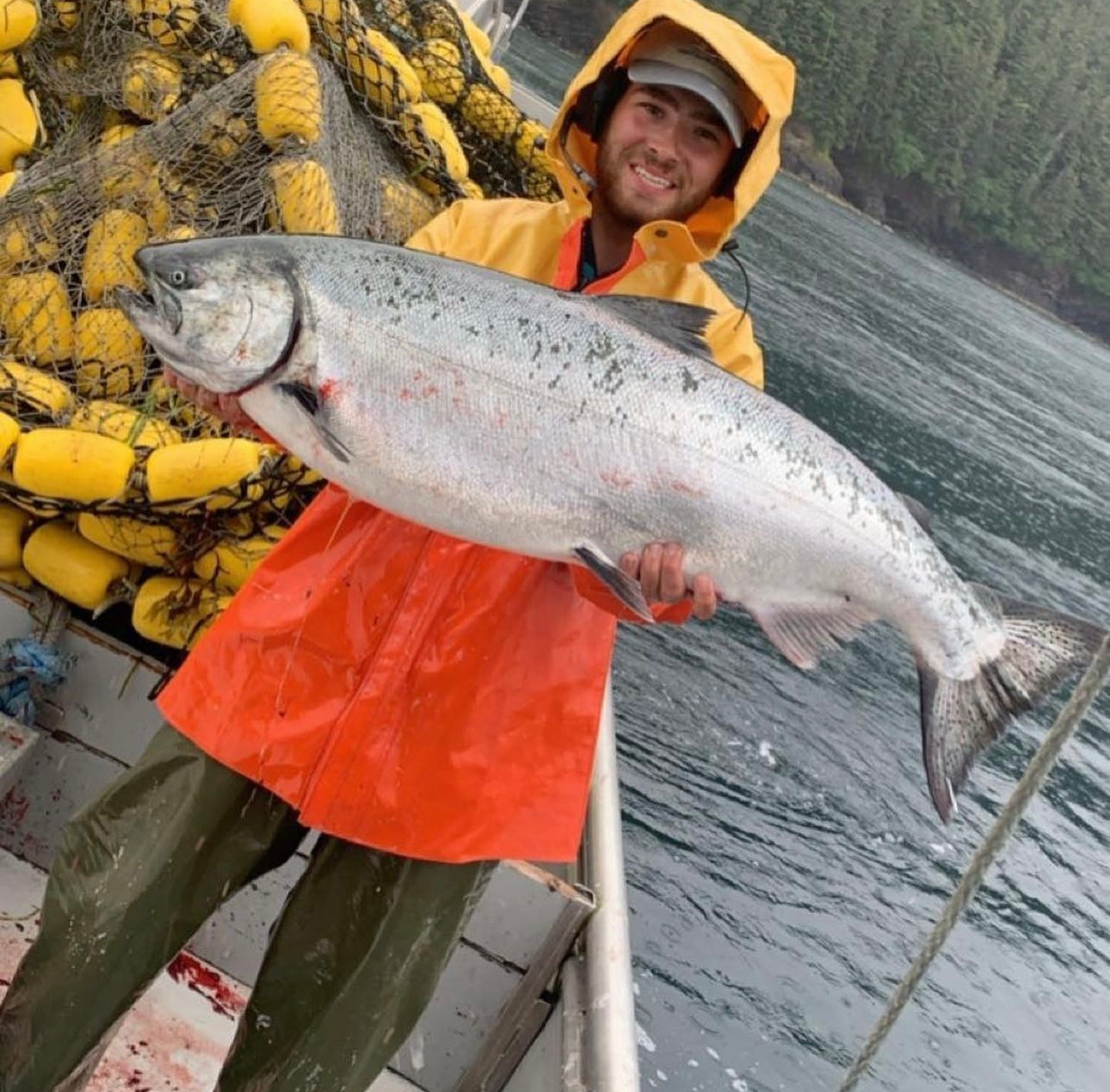 Fishing families with Matt Blake holding a large salmon on a boat.