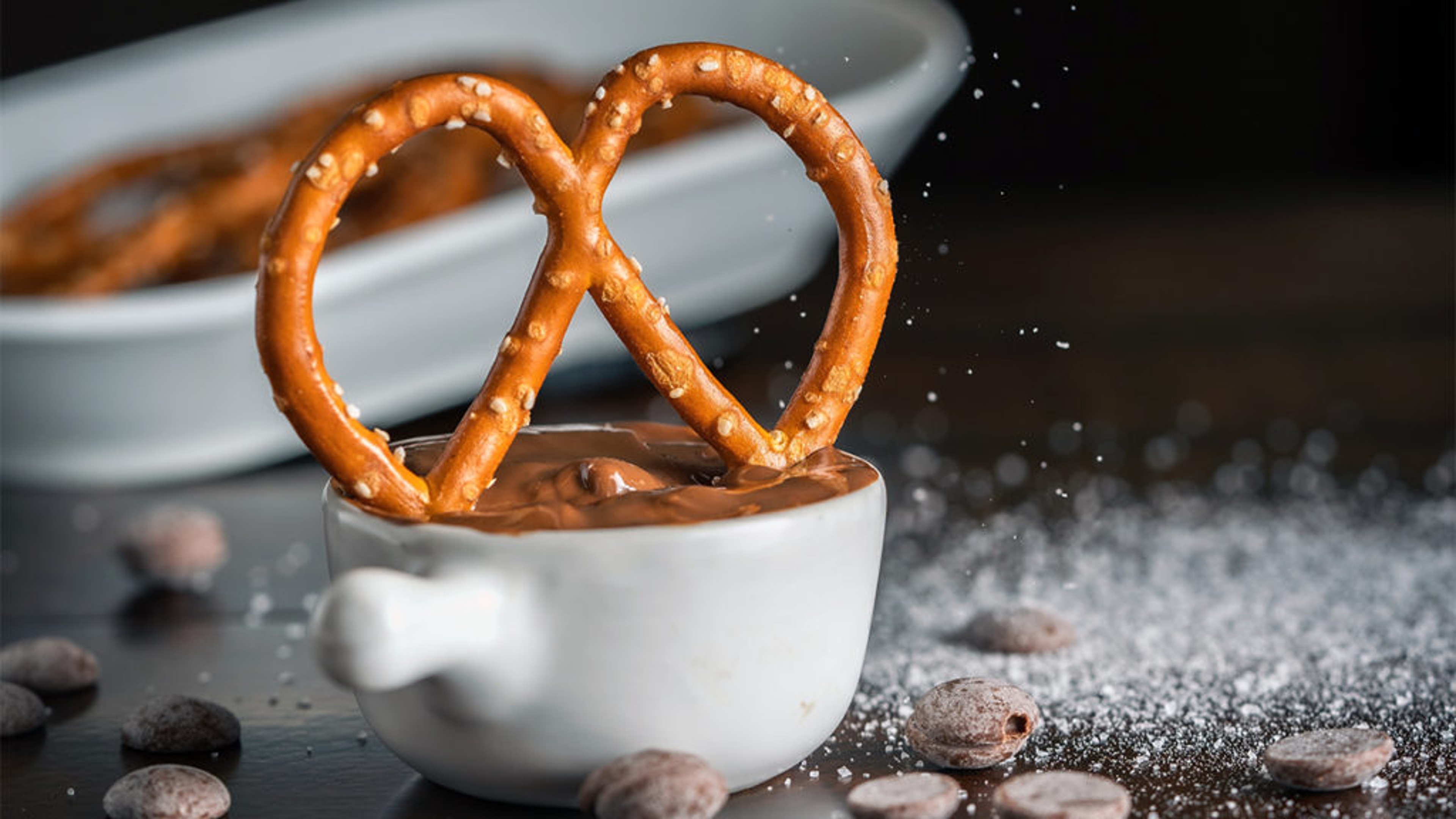 History of pretzels with a pretzel dipping into a bowl of chocolate.