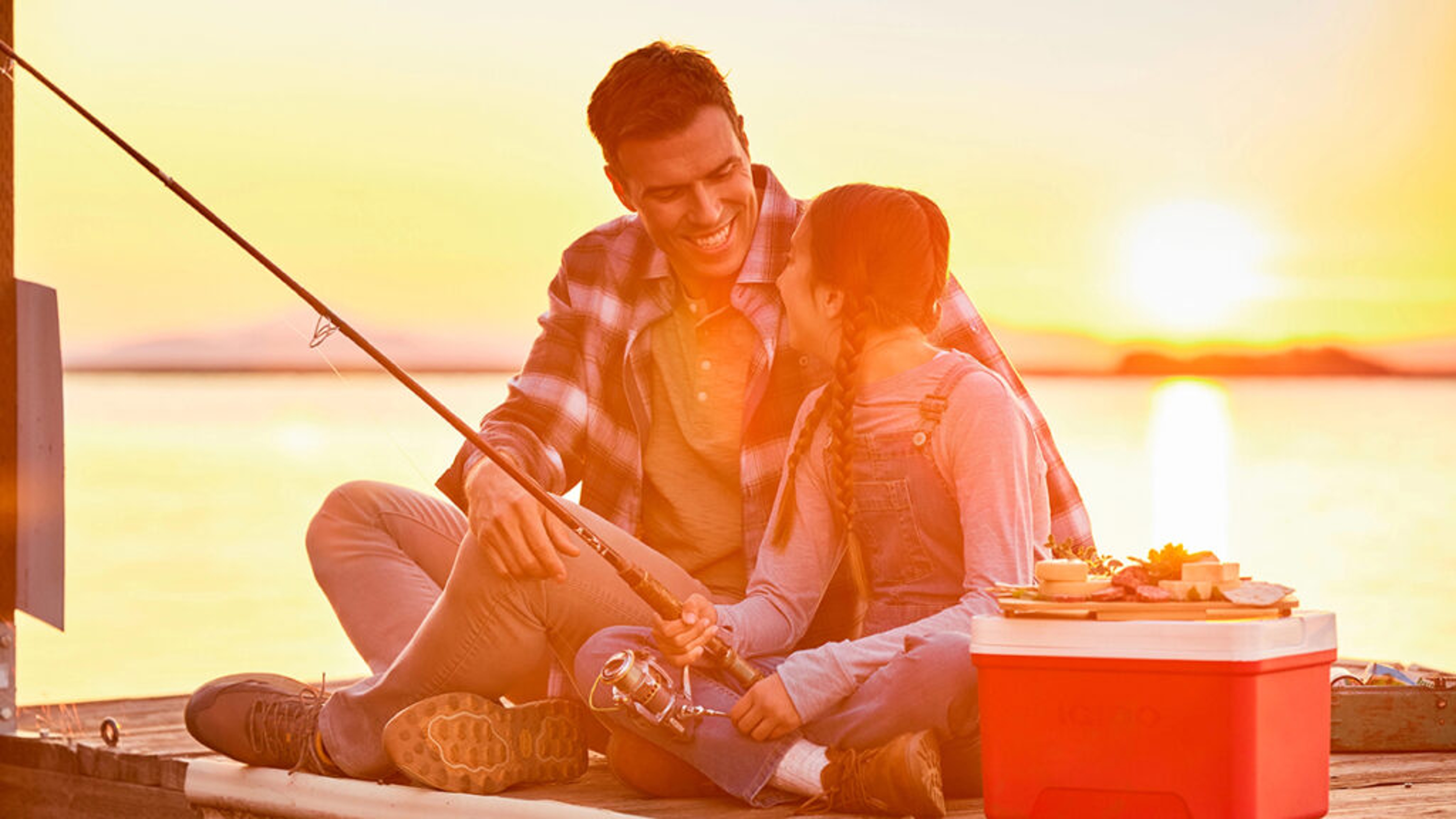 Reasons to love fish with a father and daughter fishing on a dock at sunset.