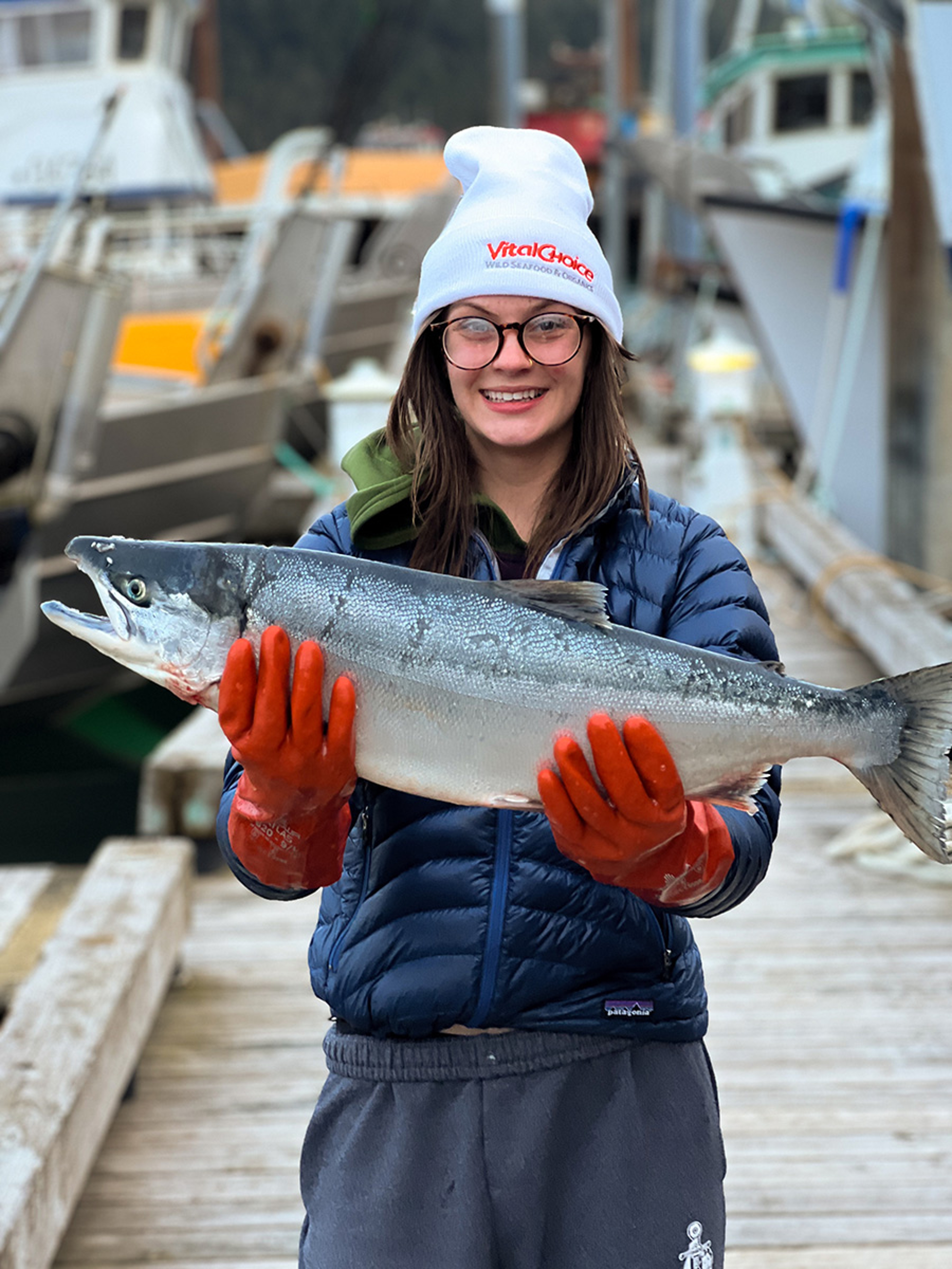 Kiley Burton, fisherman, holding up a salmon and smiling at the camera.