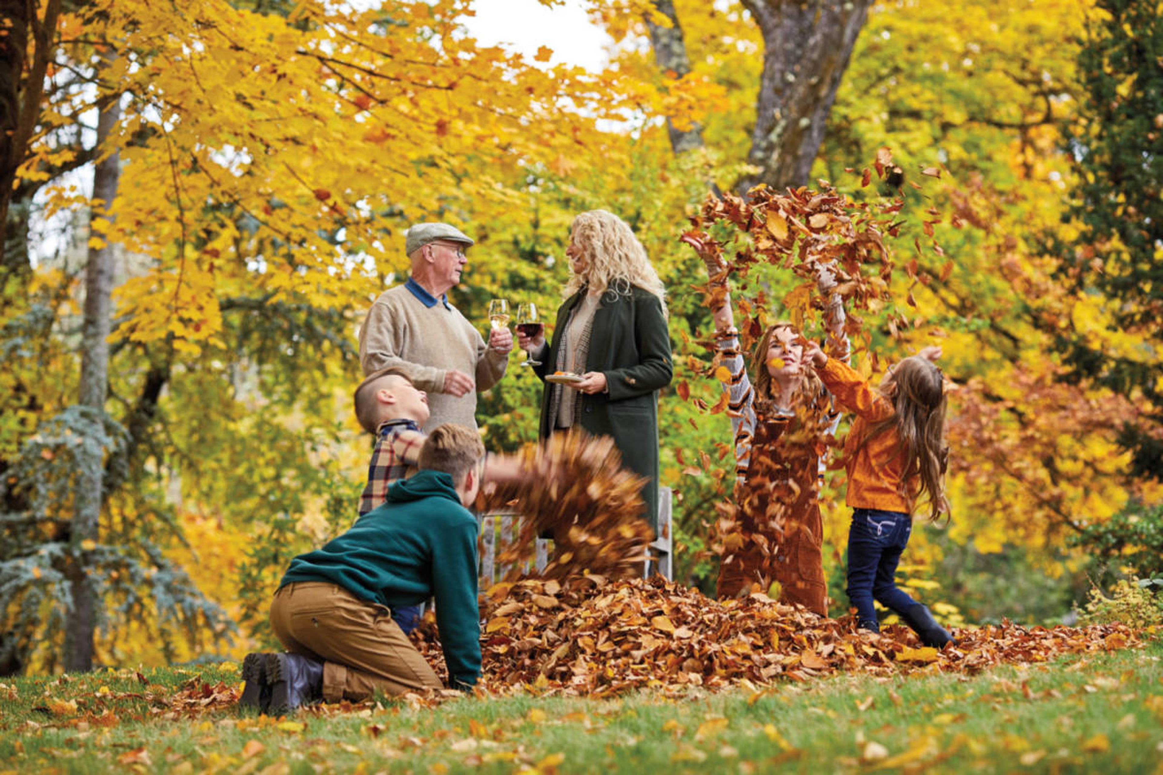 fall leaves image kids playing in leaves with two adults in the background