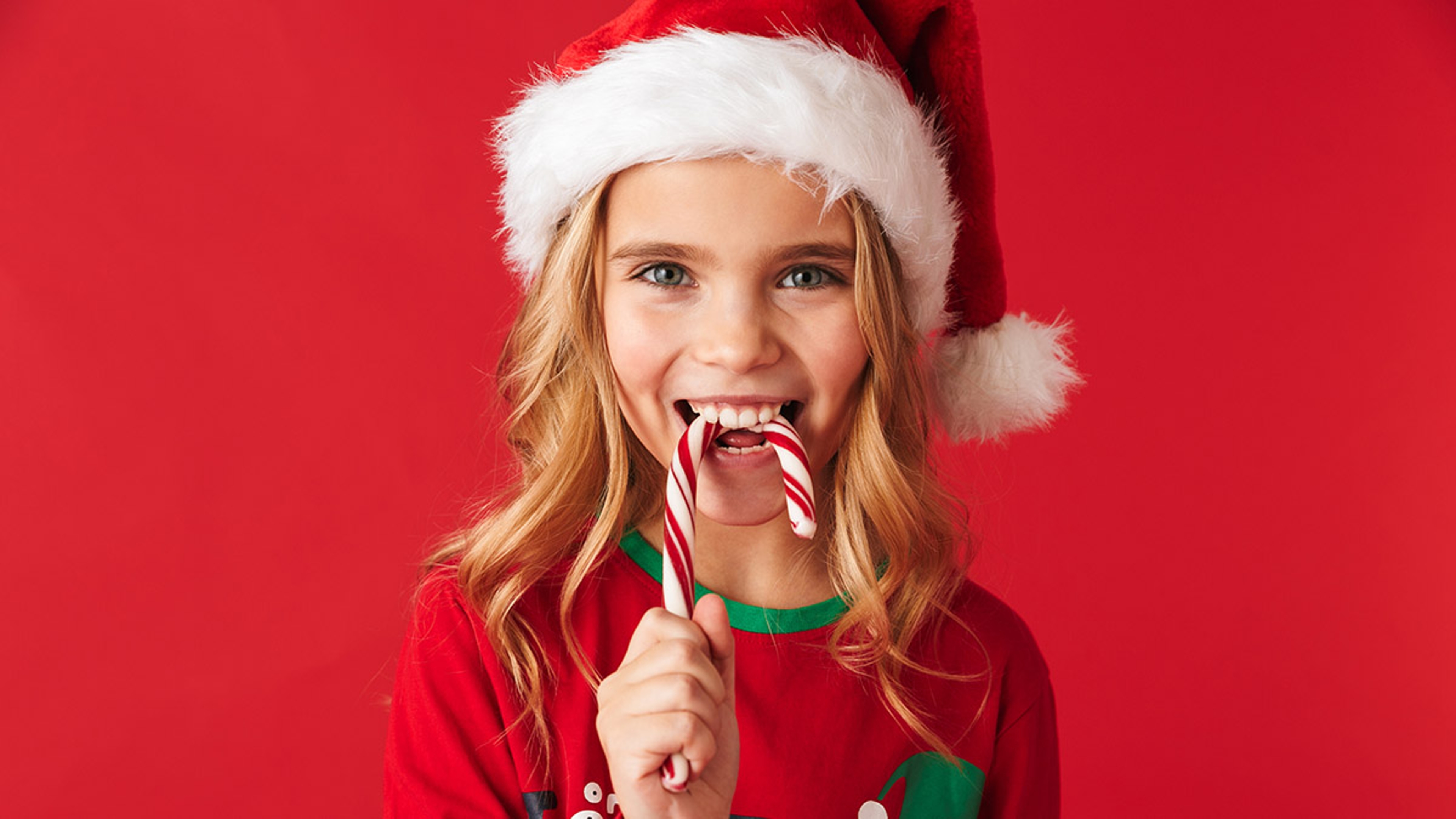 Article Cards Featured Image history of peppermint girl in santa hat eating candy cane hero