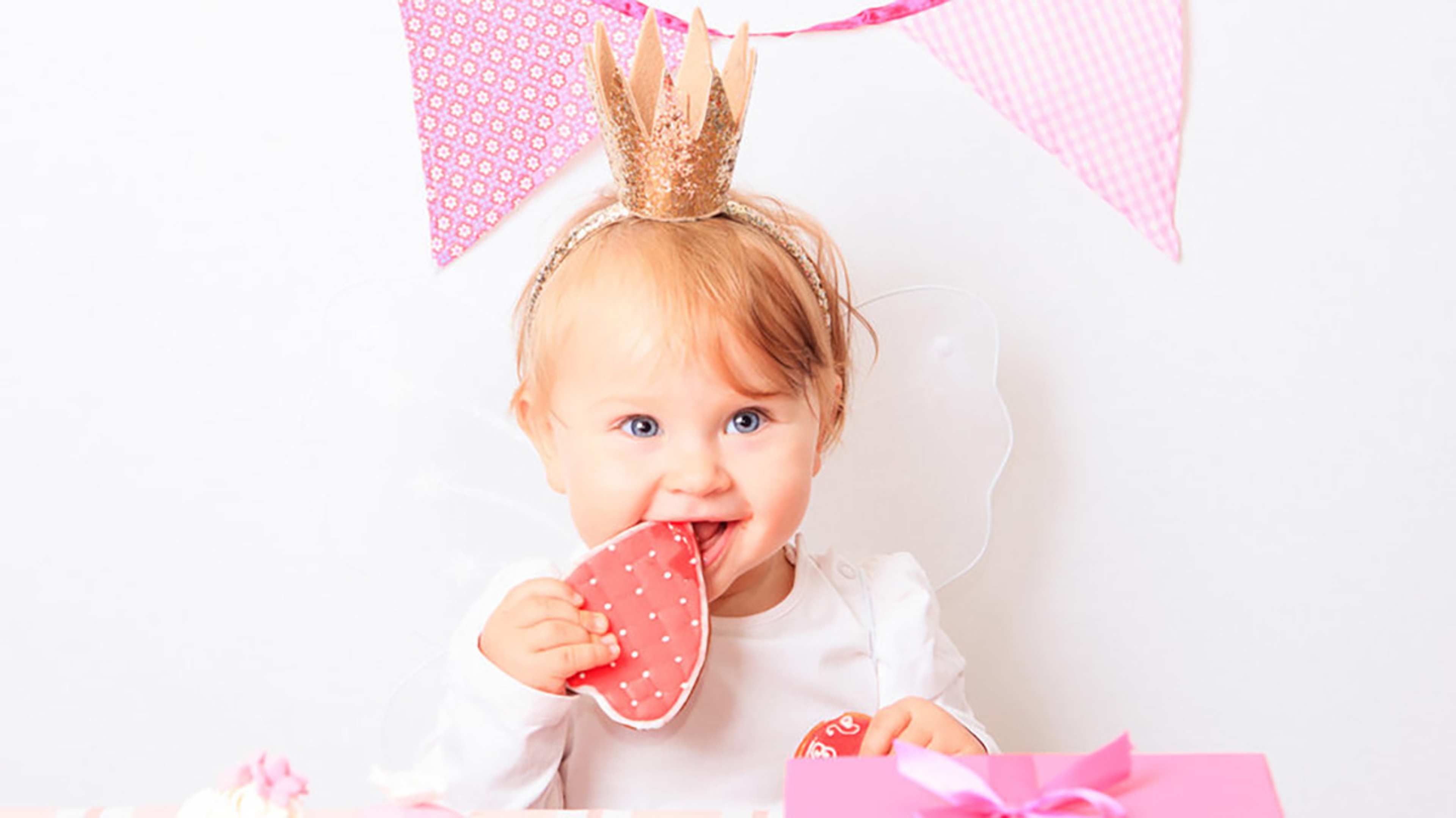 Small child eating a cookie at a first birthday party.