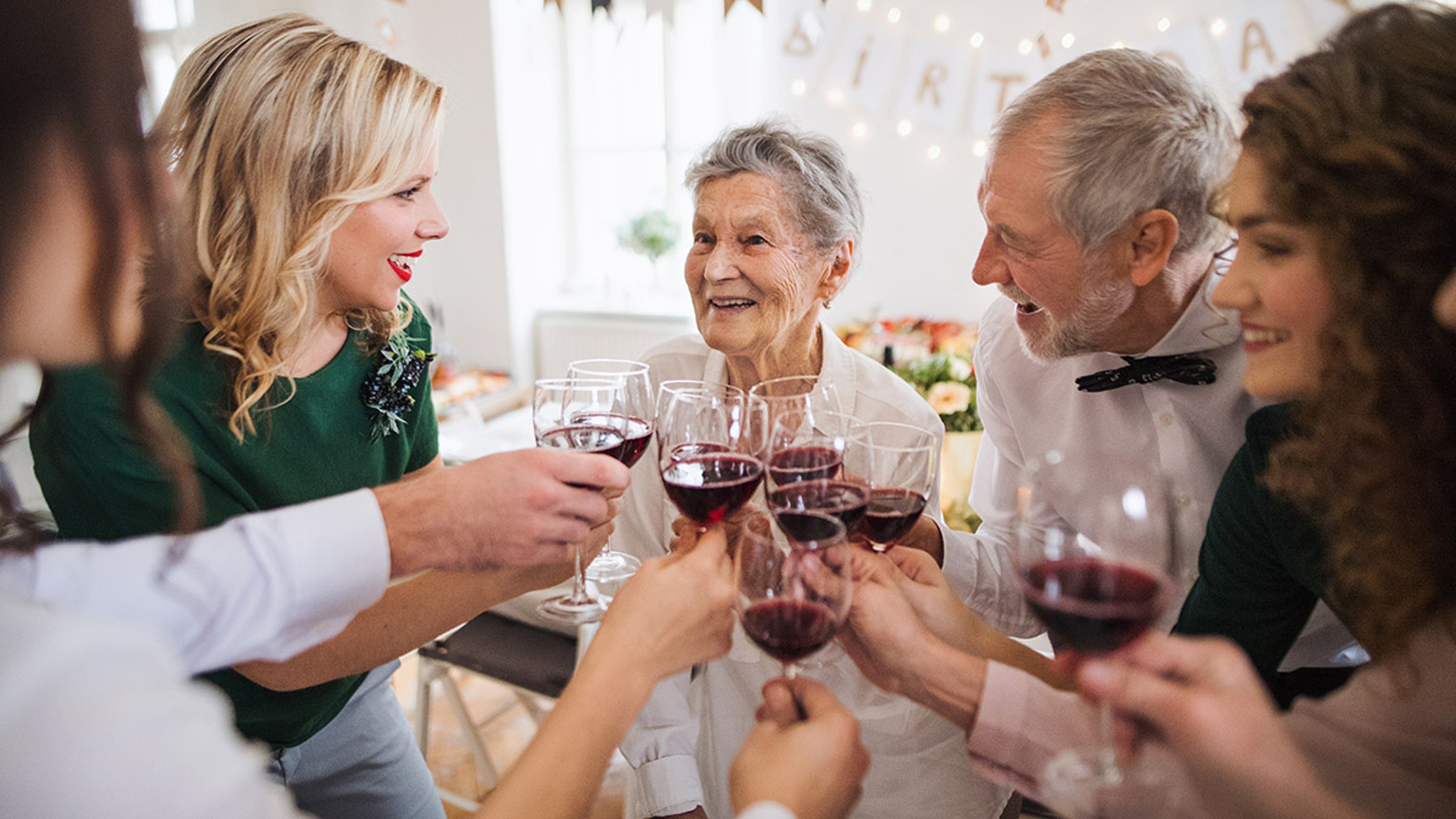 Group of adults raising glasses of wine in a toast.