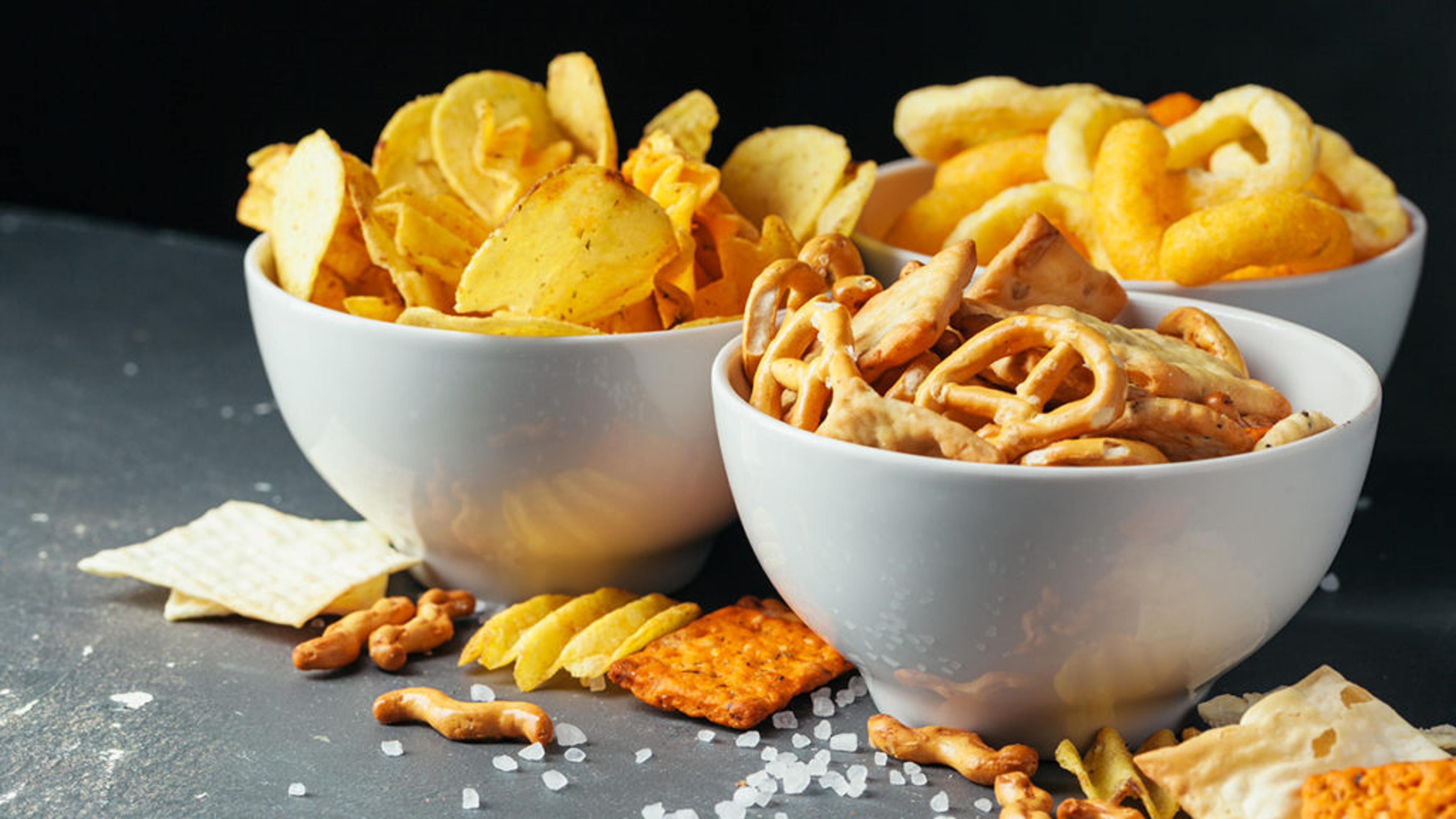 sweet and salty snacks three bowls potato chips pretzels cheese crisps